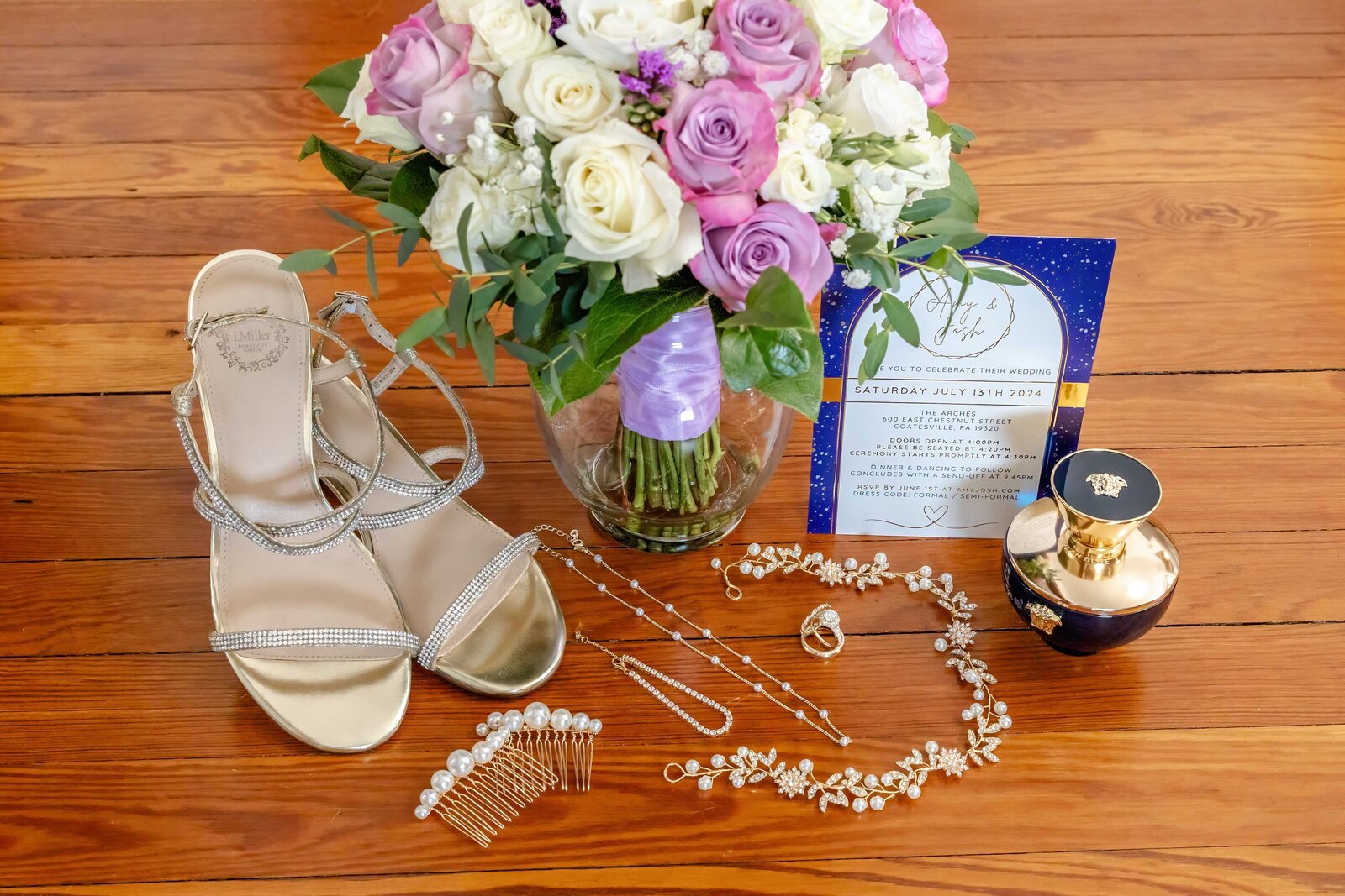 A bridal flat lay featuring gold strappy heels, a pearl necklace, wedding jewelry, a colorful bouquet, and a celestial-themed wedding invitation, captured during a PA wedding to highlight elegant and personalized details.