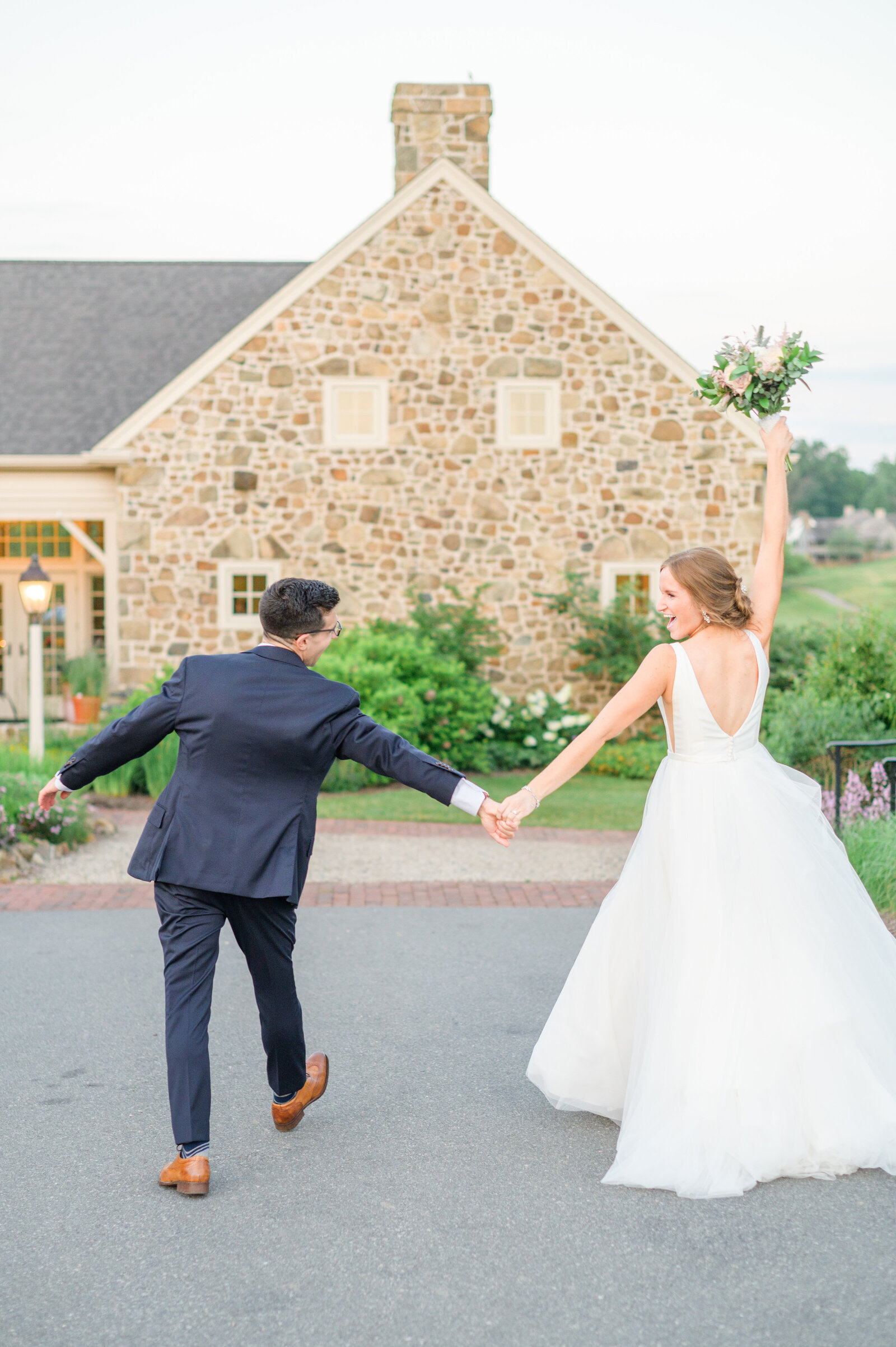 Couple celebrates in front of stone reception hall during wedding day photographed by Cait Kramer Photography