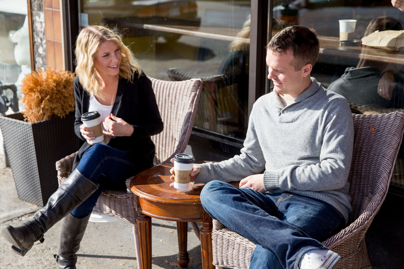 Couple sits outside coffee shop during engagement session in Toronto