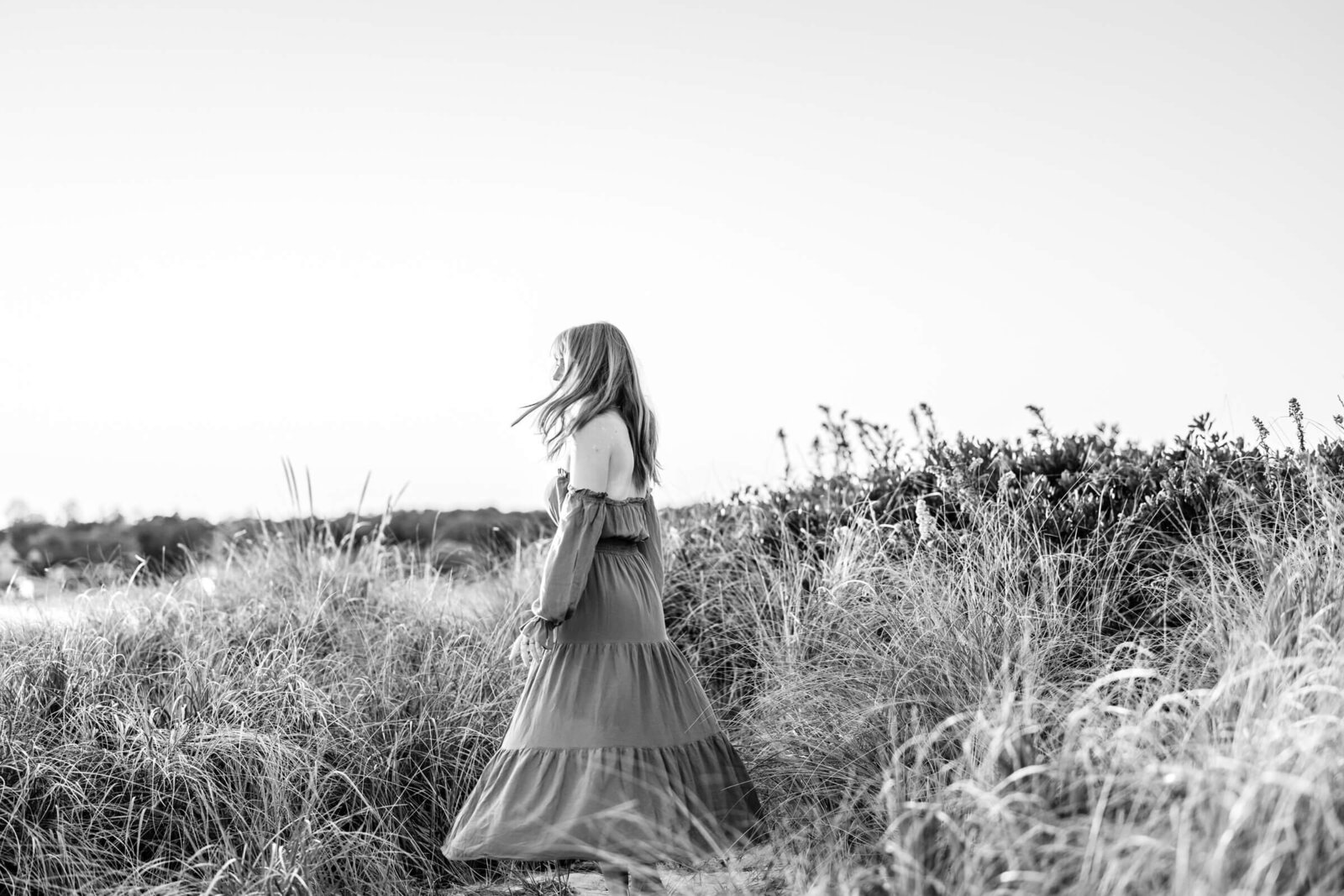 high school senior girl spins in black and white photo near beach at harkness memorial state park