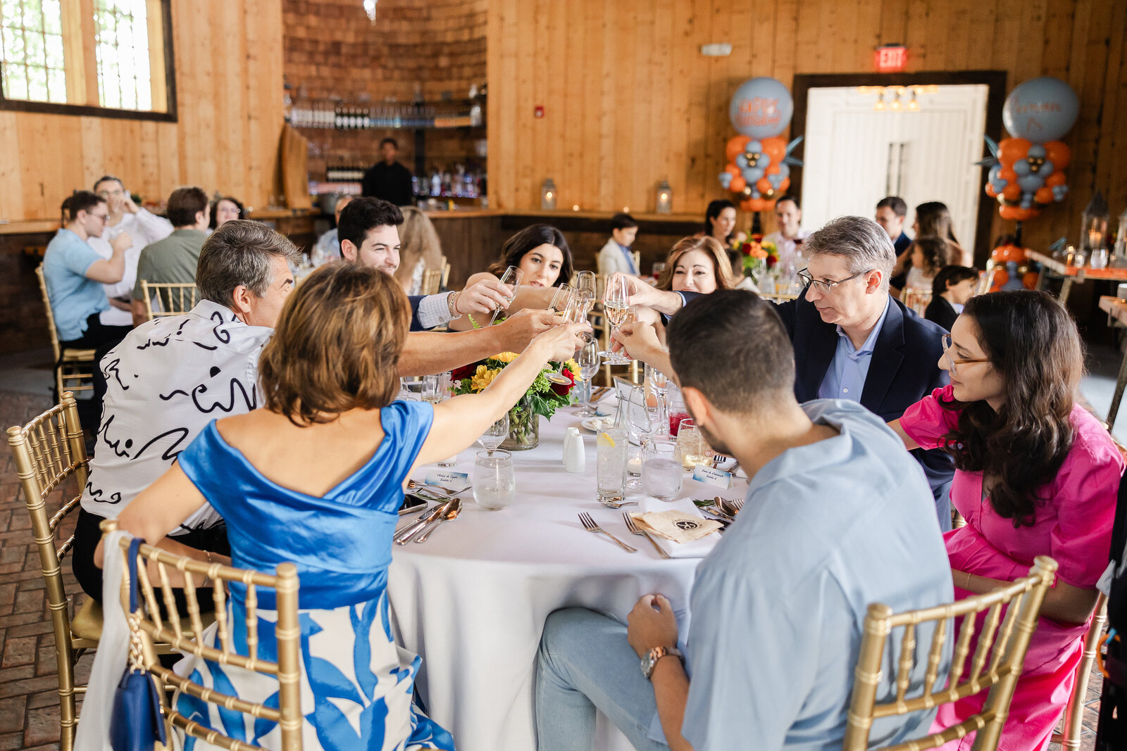 Guests clink wine glasses after a birthday toast.