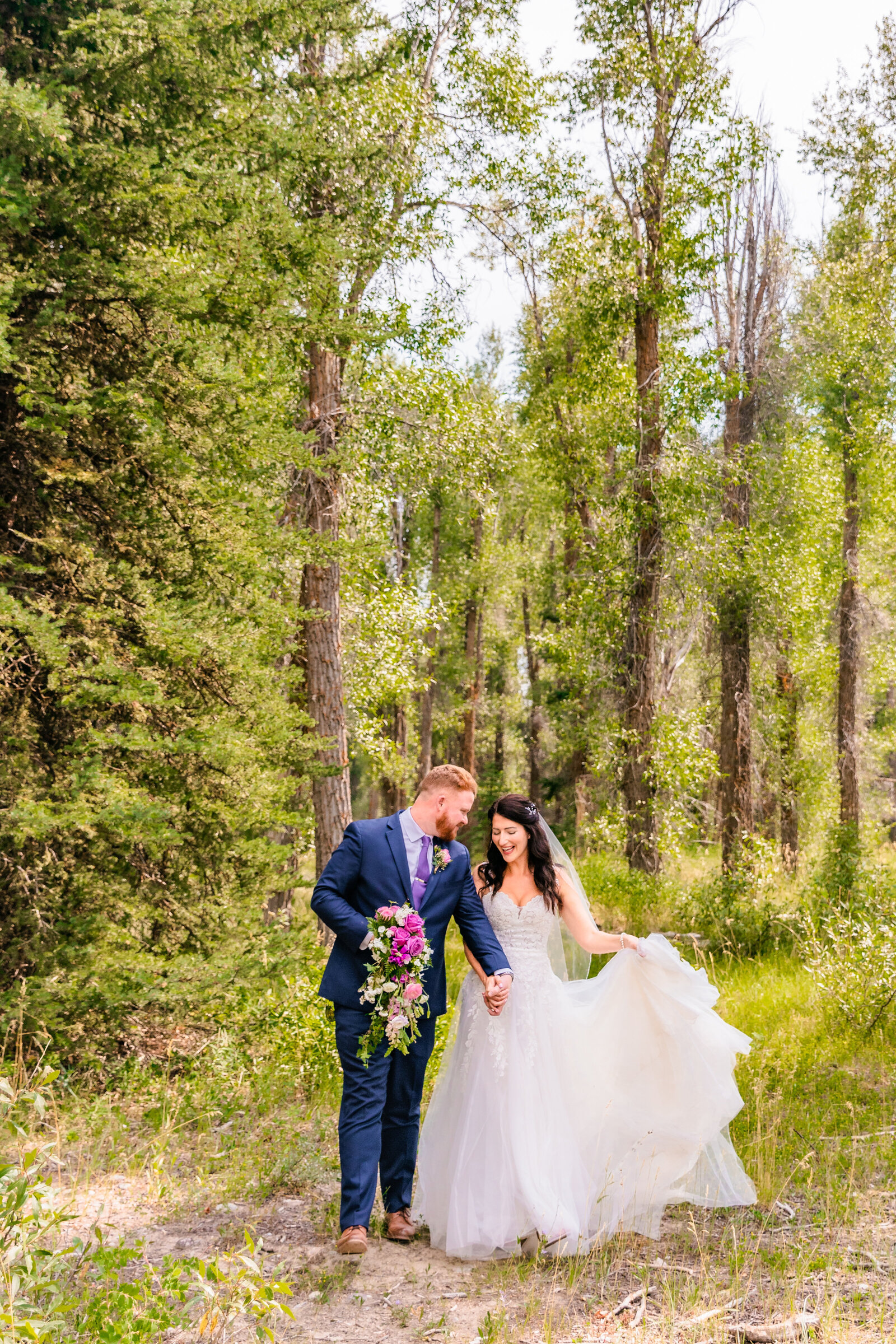 Jackson Hole photographers capture couple walking through forest during bridal portraits