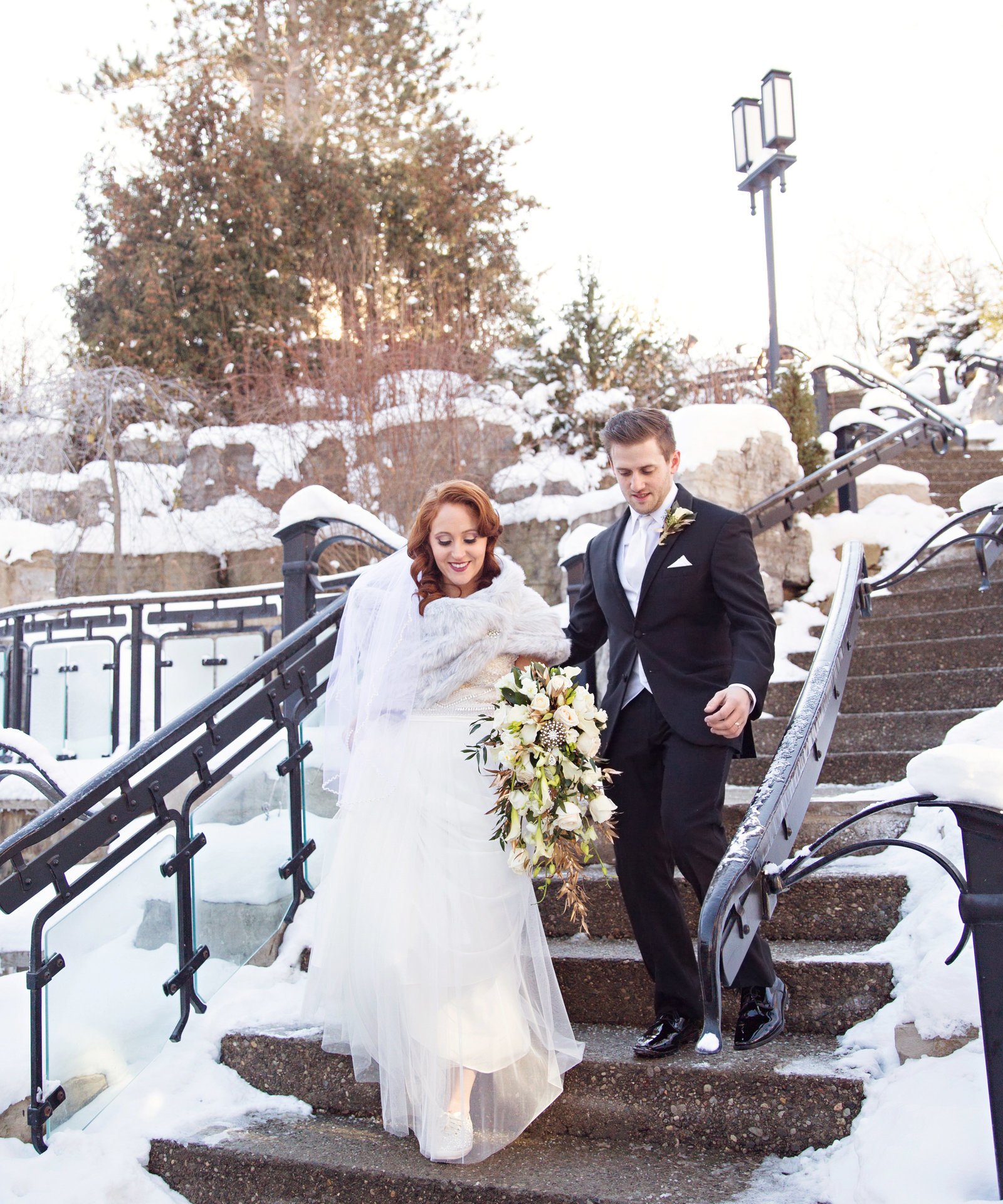 wedding couple on snowy winter stairs at the Ancaster Mill