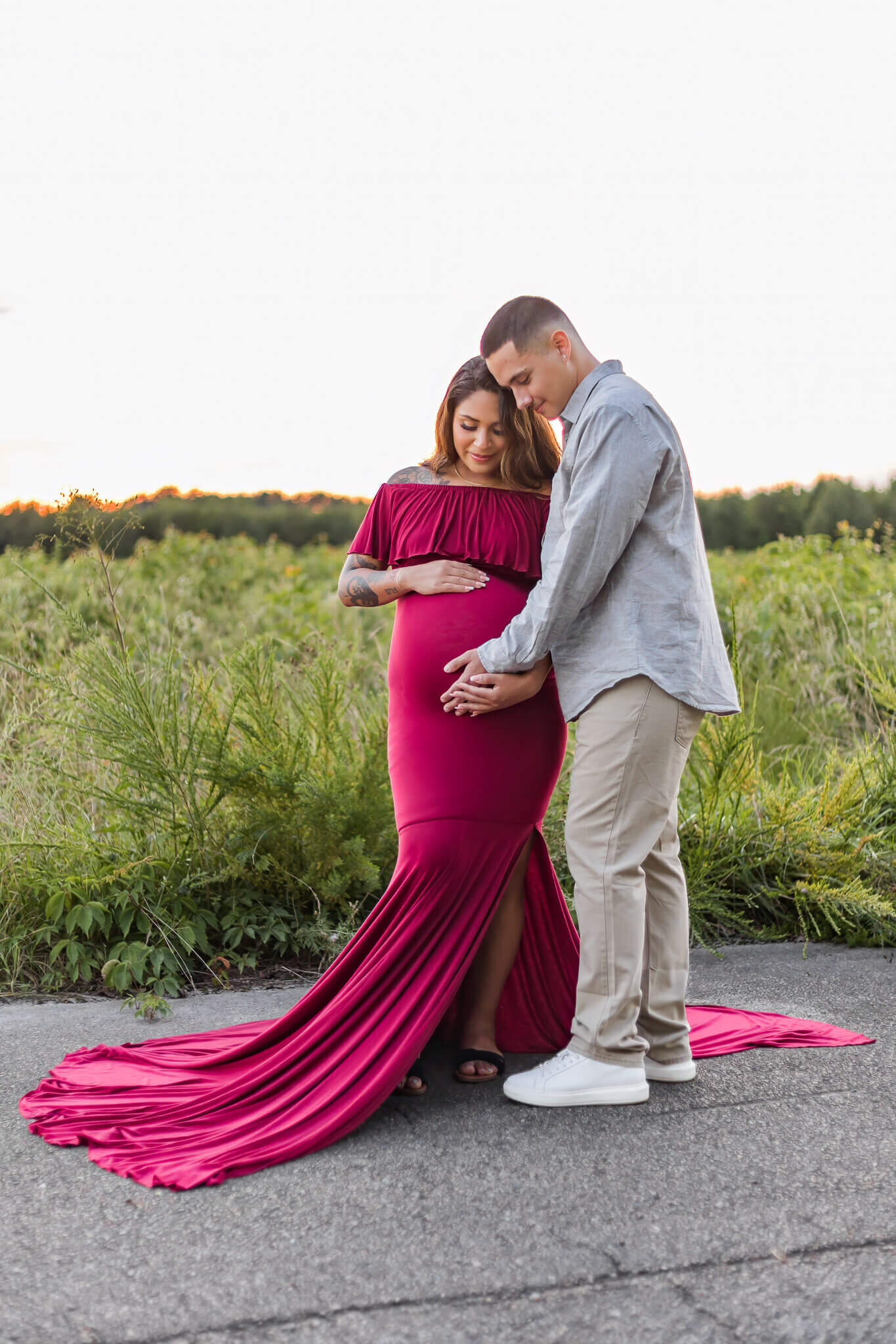 An expecting couple snuggled up together and holding mom's belly.