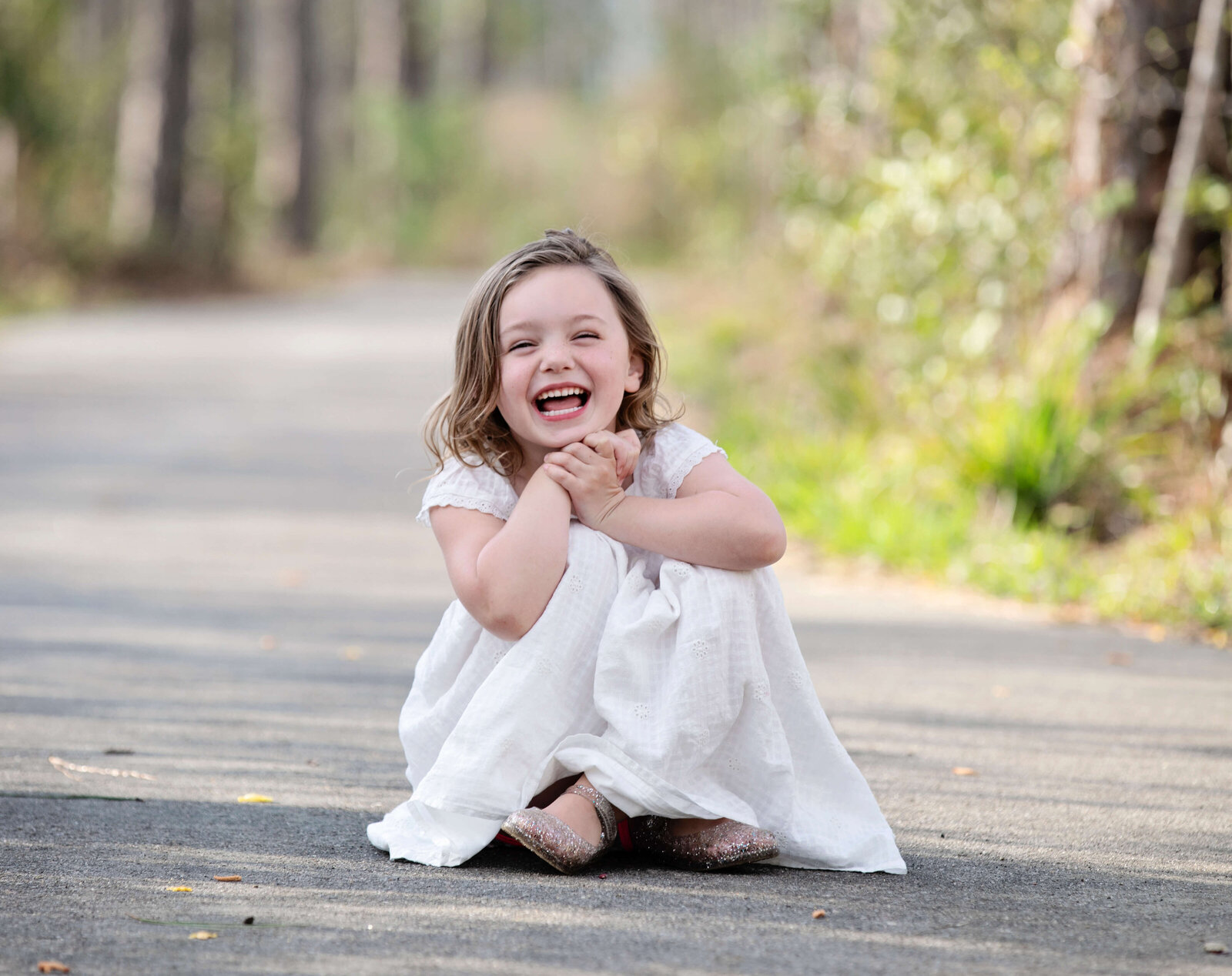Photo of little girl sitting in a pathway laughing in Erie Pa