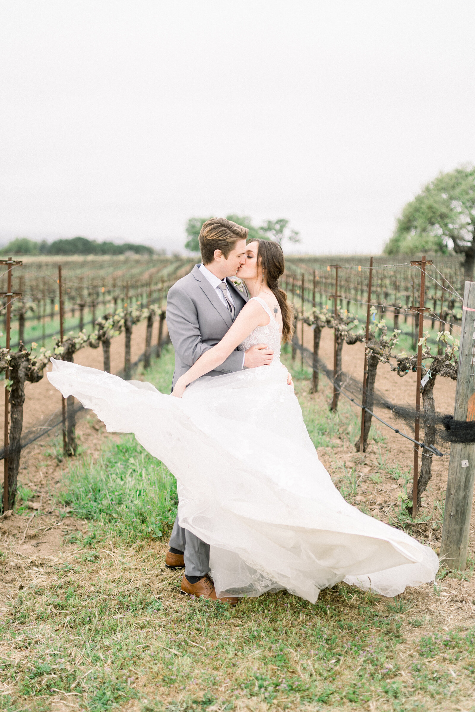 This romantic image by Tiffany Longeway features a bride and groom sharing a kiss in the vineyards of Sunstone Winery in Santa Ynez, CA, capturing the essence of vineyard romance.