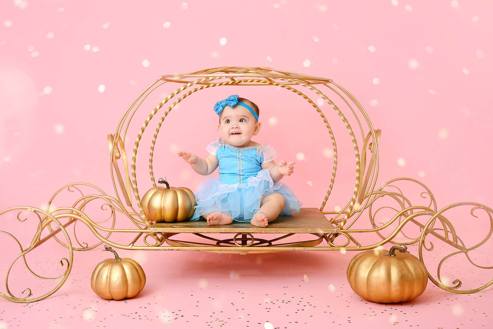birthday girl sits in a golden carriage at her first birthday session in houston