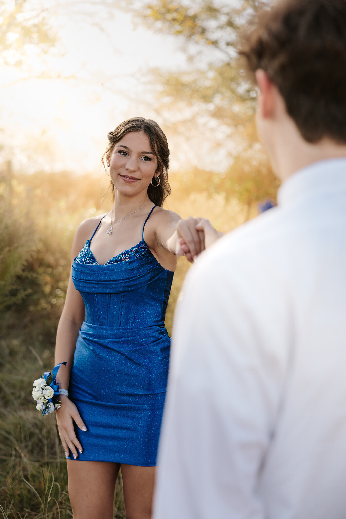 Outdoor homecoming photoshoot in Aiken SC - teen girl in a blue HOCO dress smiling at her date during golden hour.