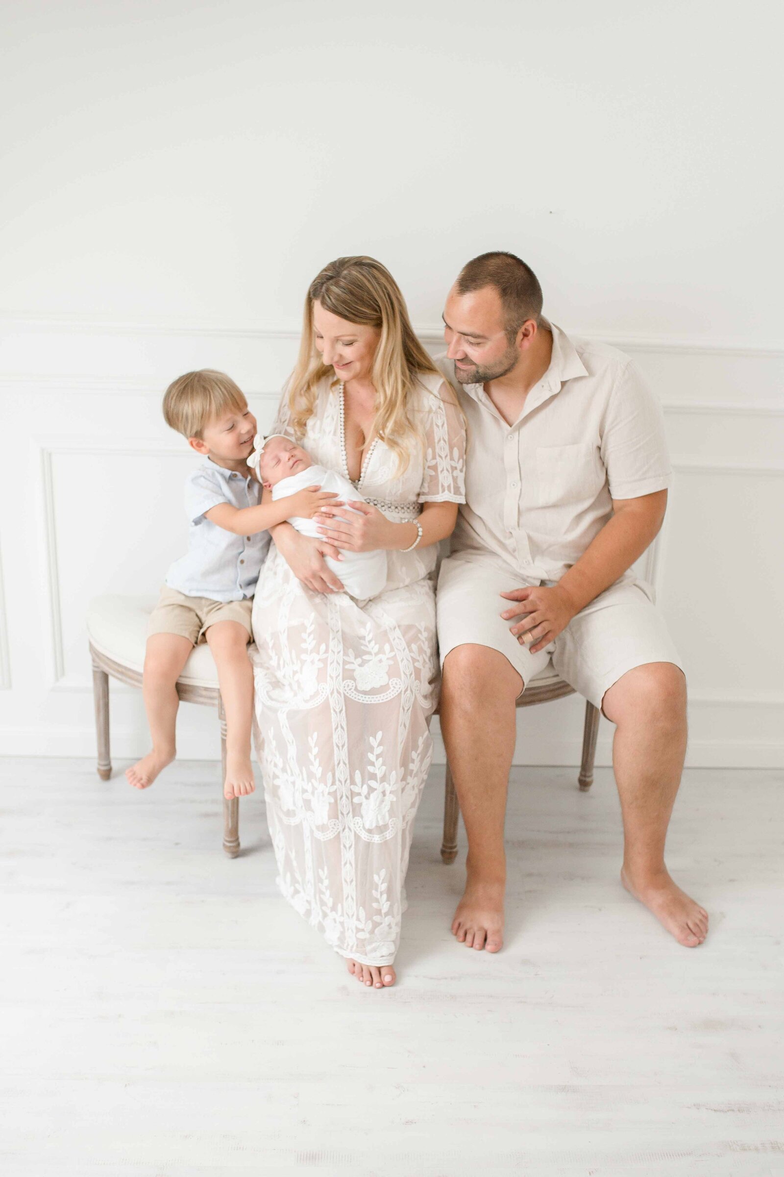 Familienfotoshooting im Fotostudio Gütersloh bei Bielefeld und Rietberg. Eltern, Kleinkind und Baby auf einer Polsterbank.