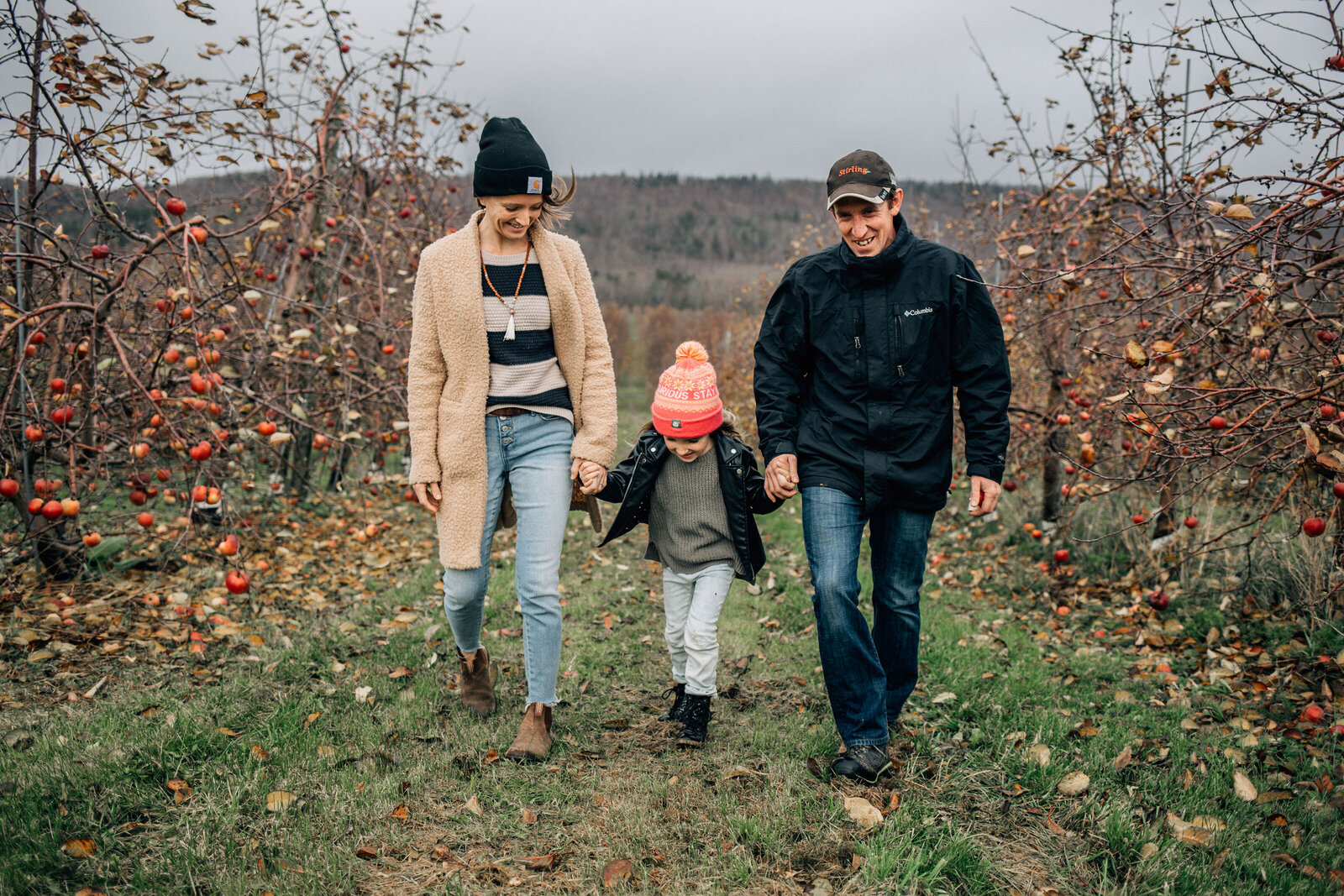 family walking through apple orchard in the fall