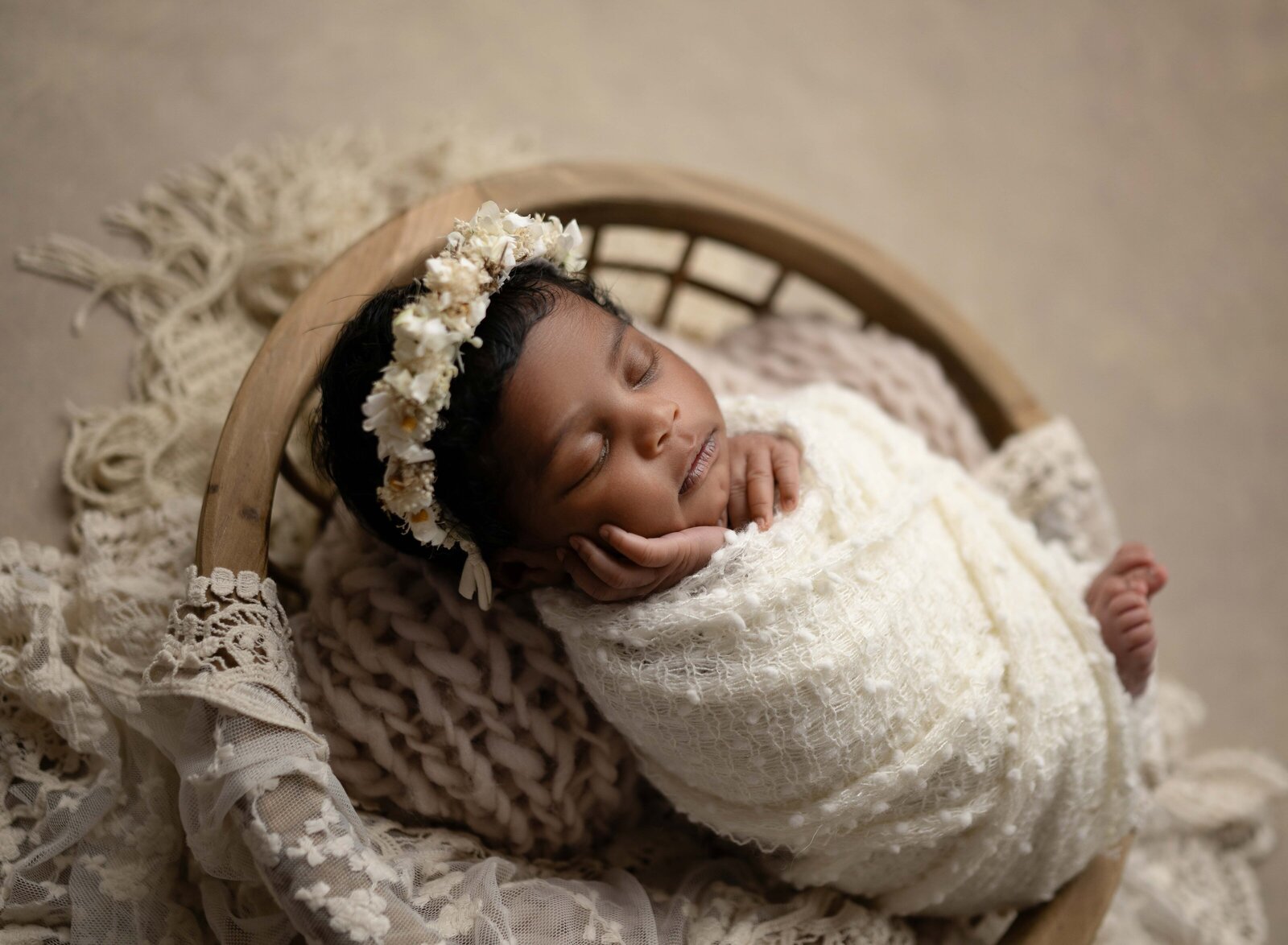 Baby swaddled and sleeping in wooden bowl with her hand on her cheek. Photographed by Jenni Nikki Photography at Marietta Newborn Photo Studio.