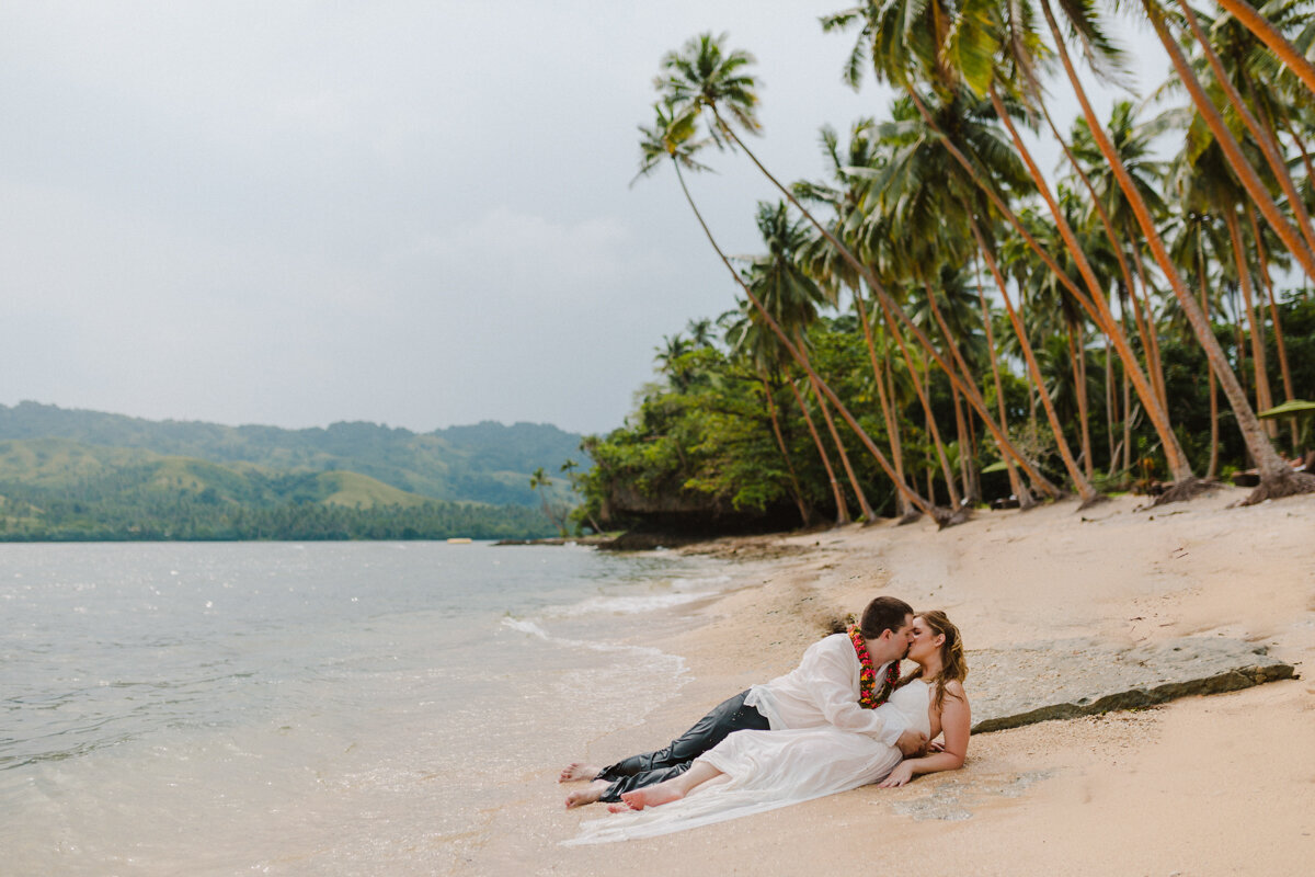 bride and groom reclining on beach