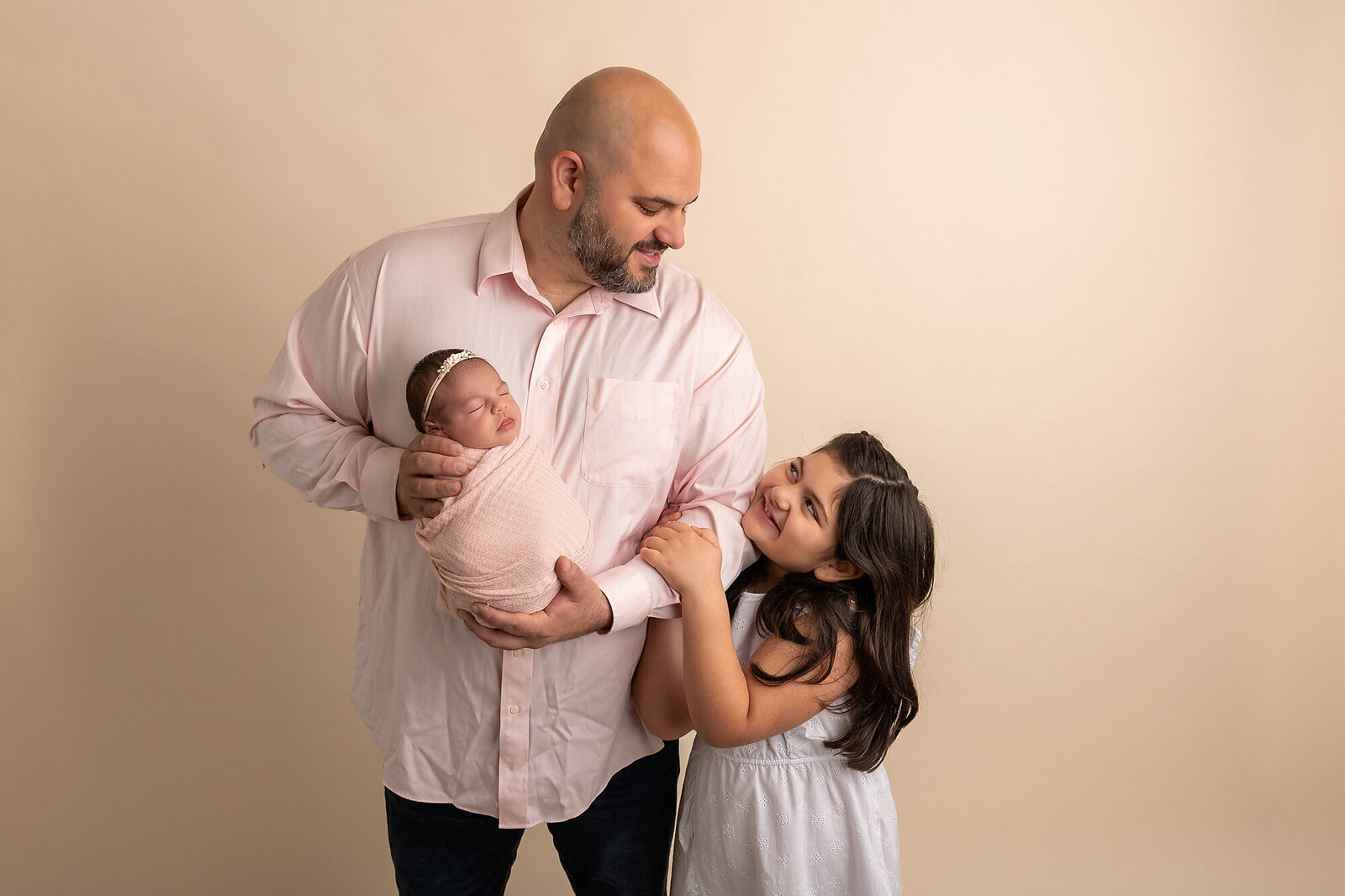 dad holding baby girl with older sister by Newborn Photography Bucks County PA