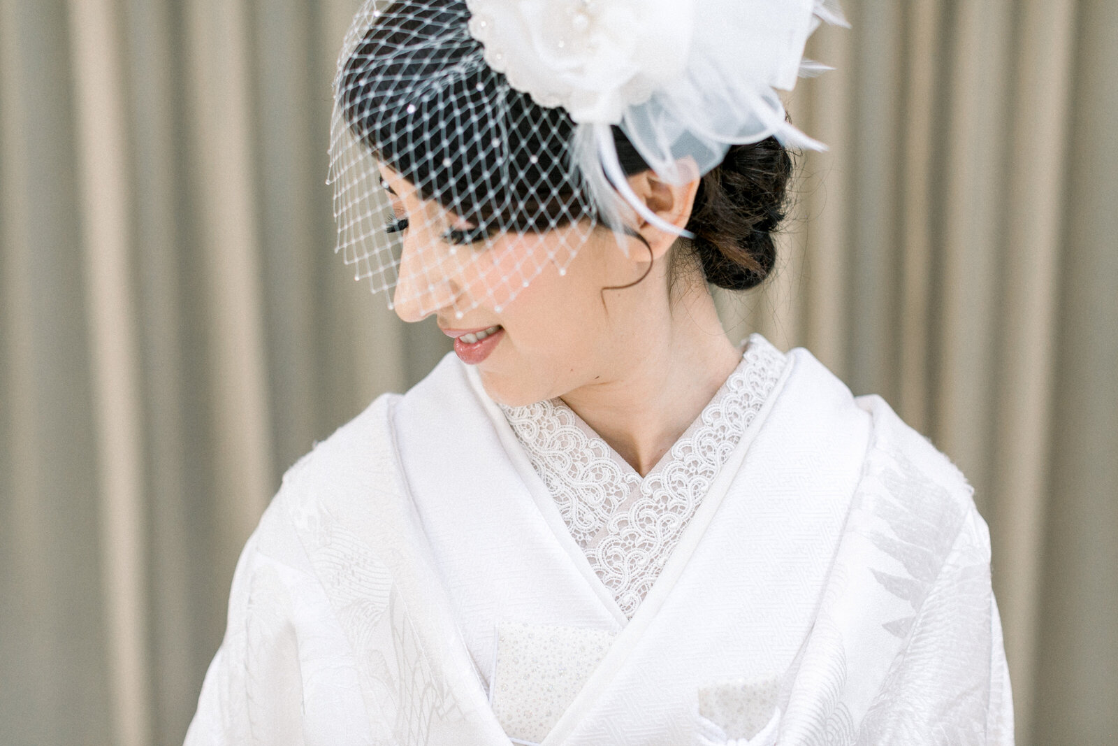 Close-up bridal portrait in a white shiromuku with a birdcage veil, taken at The Ebell Club Long Beach in Los Angeles, California. Available for wedding kimono rental in Los Angeles | エベルクラブ（ロサンゼルス・カリフォルニア）で撮影された、バードケージベールをつけた白無垢花嫁のクローズアップポートレート。着物レンタル可能。