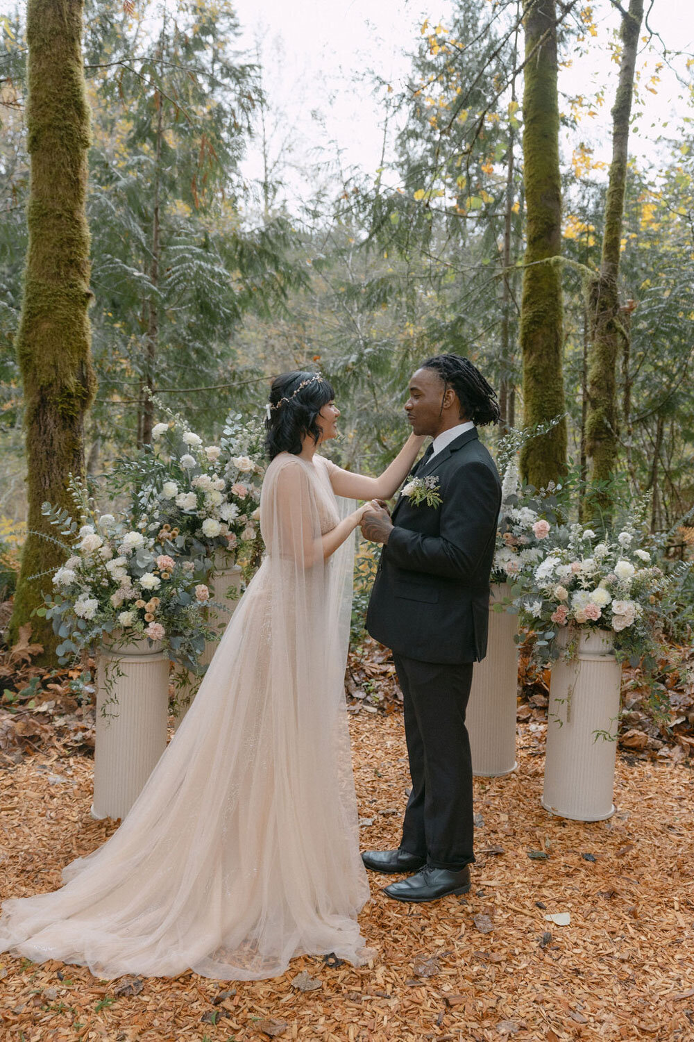 Bride and groom exchanging vows surrounded by floral arrangements