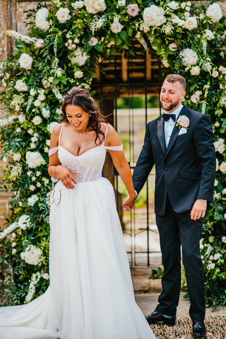 A bride and groom smiling and holding hands