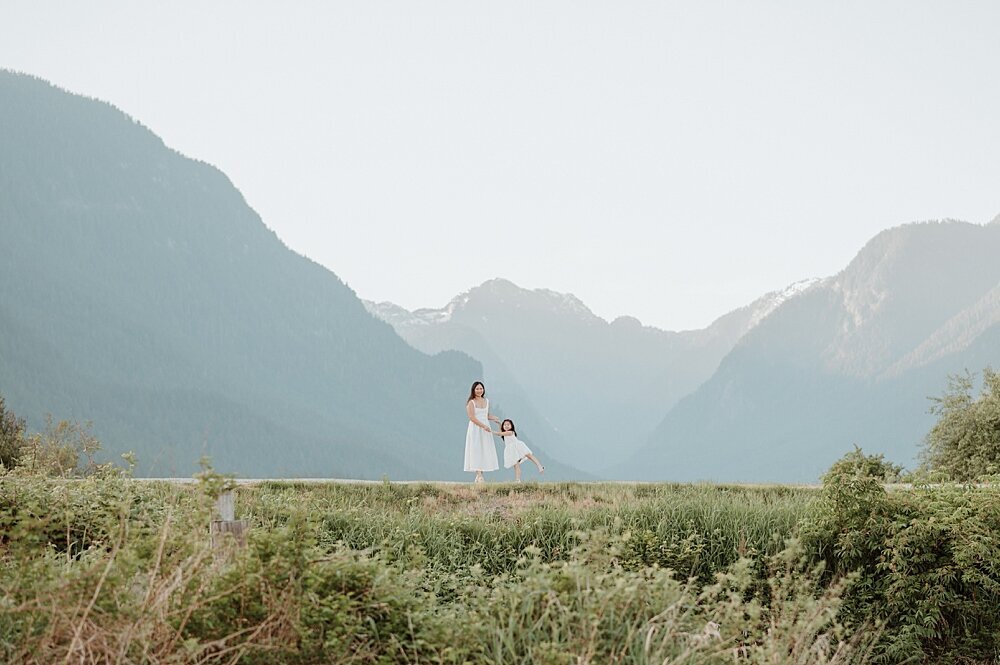 Mom and daughter dancing on a path with a mountain view with Vancouver Family Photographer
