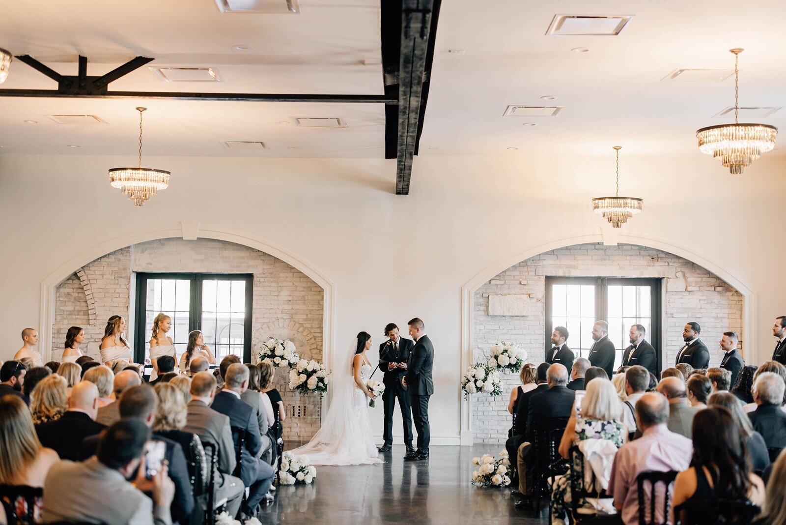 indoor wedding ceremony in the luxe room sorrounded by their guests