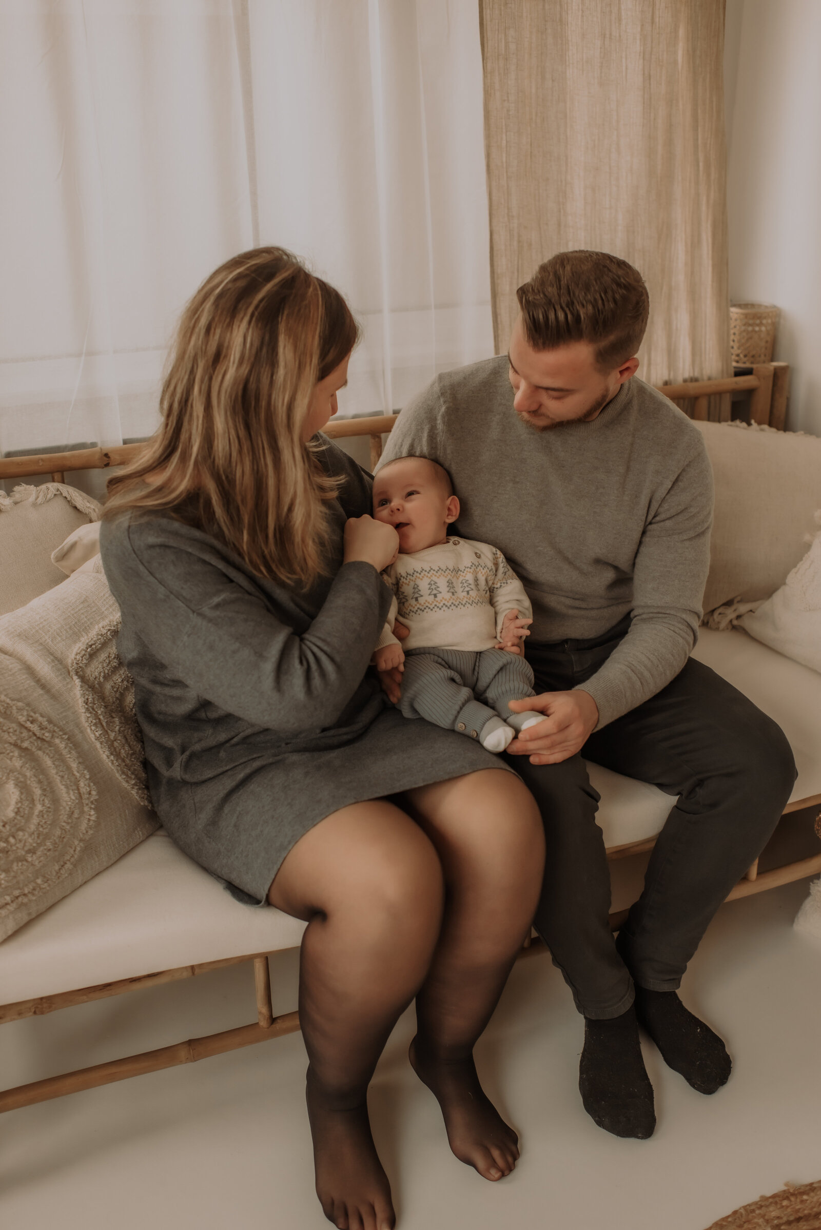 Trotse ouders kijken naar hun zoontje tijdens familie fotoshoot in daglicht studio te Antwerpen