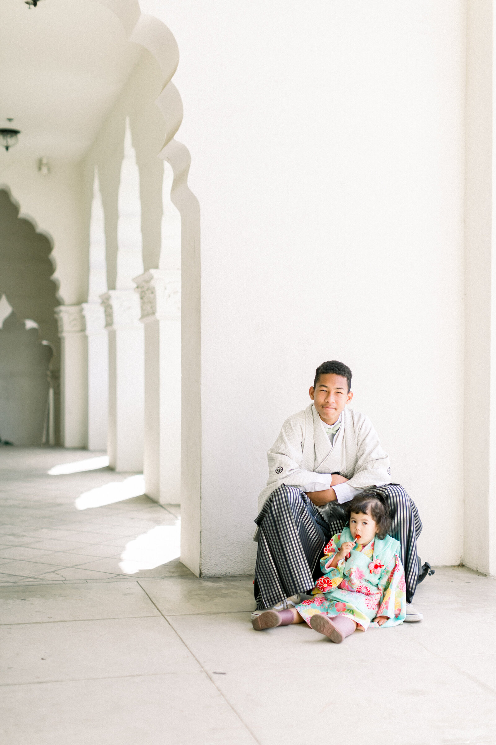 Older brother in formal hakama sitting with his little sister in a colorful kimono at Brand Park Glendale for Seijinshiki, kimono rental Los Angeles | ロサンゼルス・ブランドパークでの成人式、袴姿の兄と華やかな着物の妹が並ぶ心温まるシーン