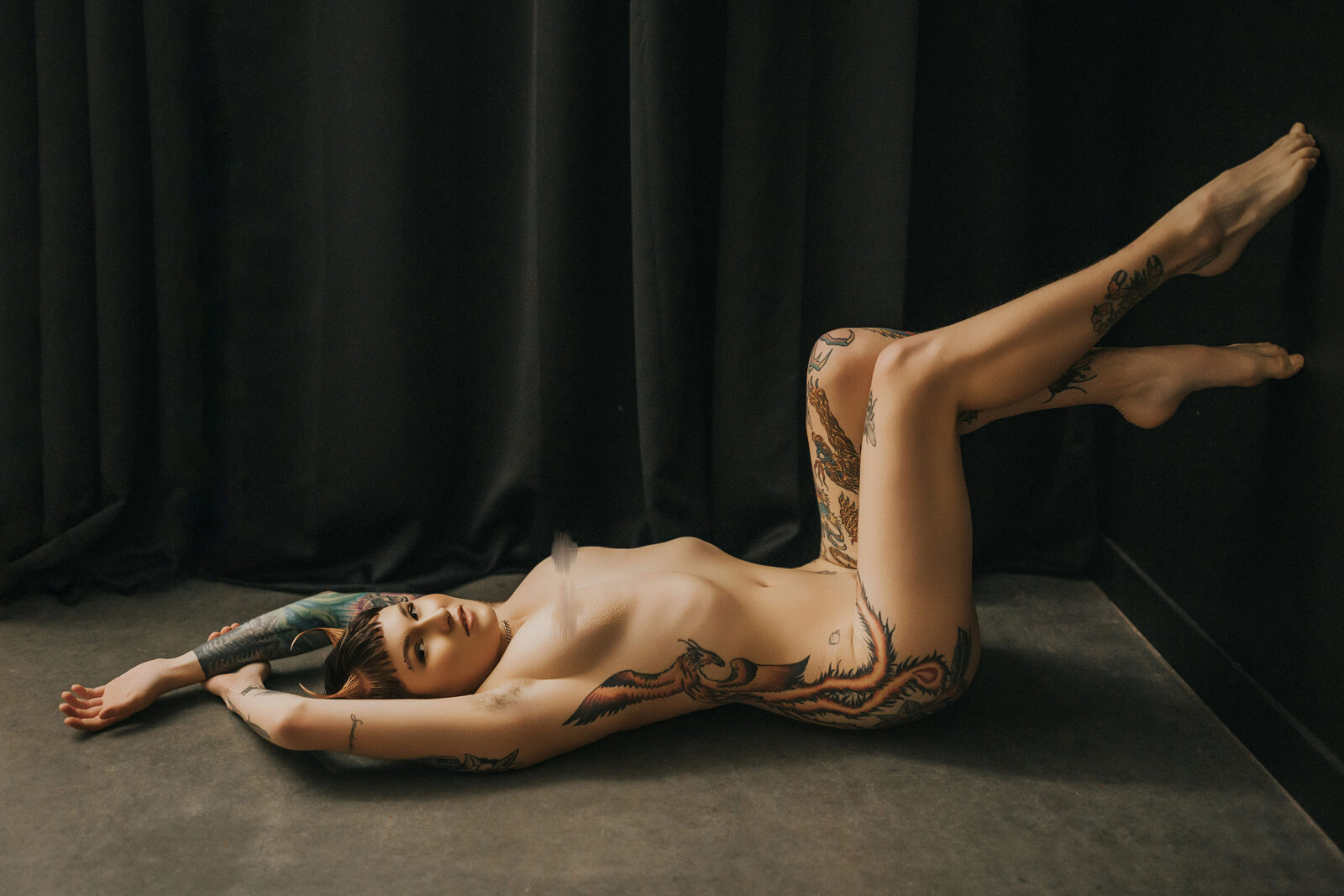 non binary person posing on the floor during boudoir photoshoot