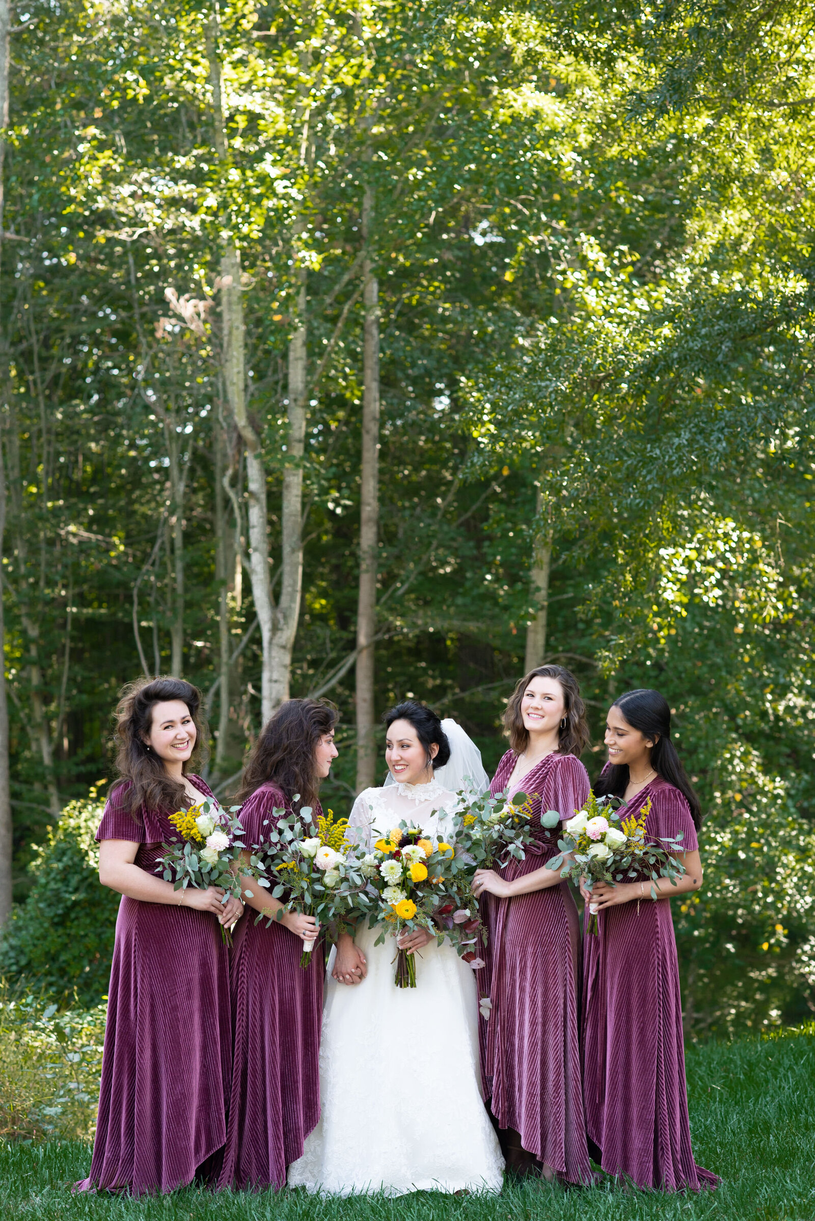 A bride stands with her bridesmaids in a field.