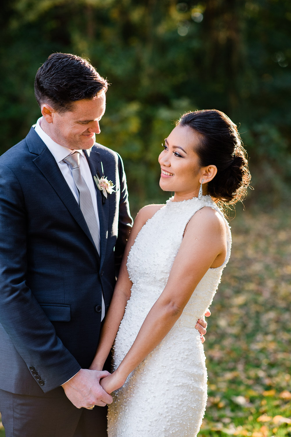 bride and groom look at each other holding  hands