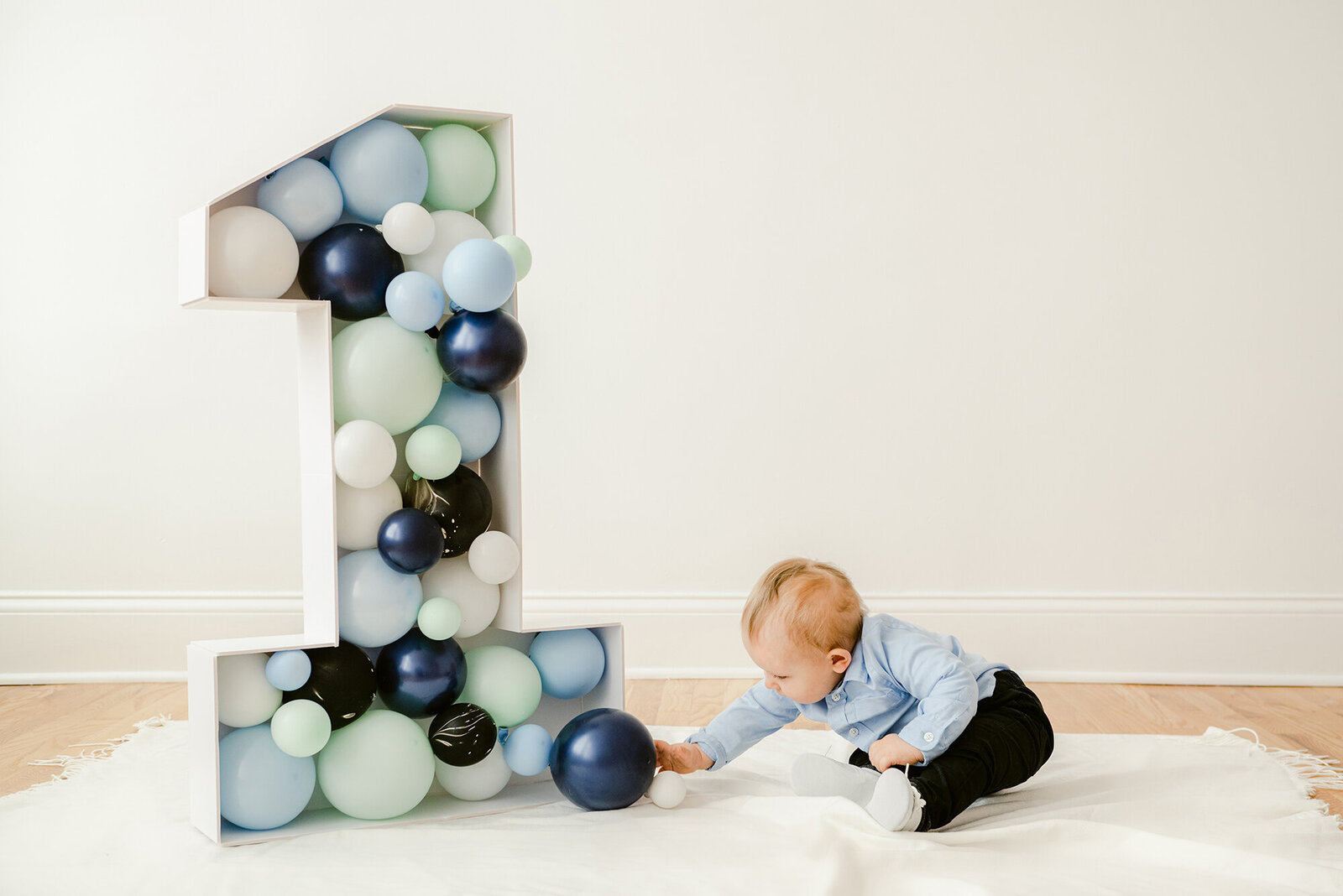 Baby reaching for a balloon for his first birthday photos in the studio