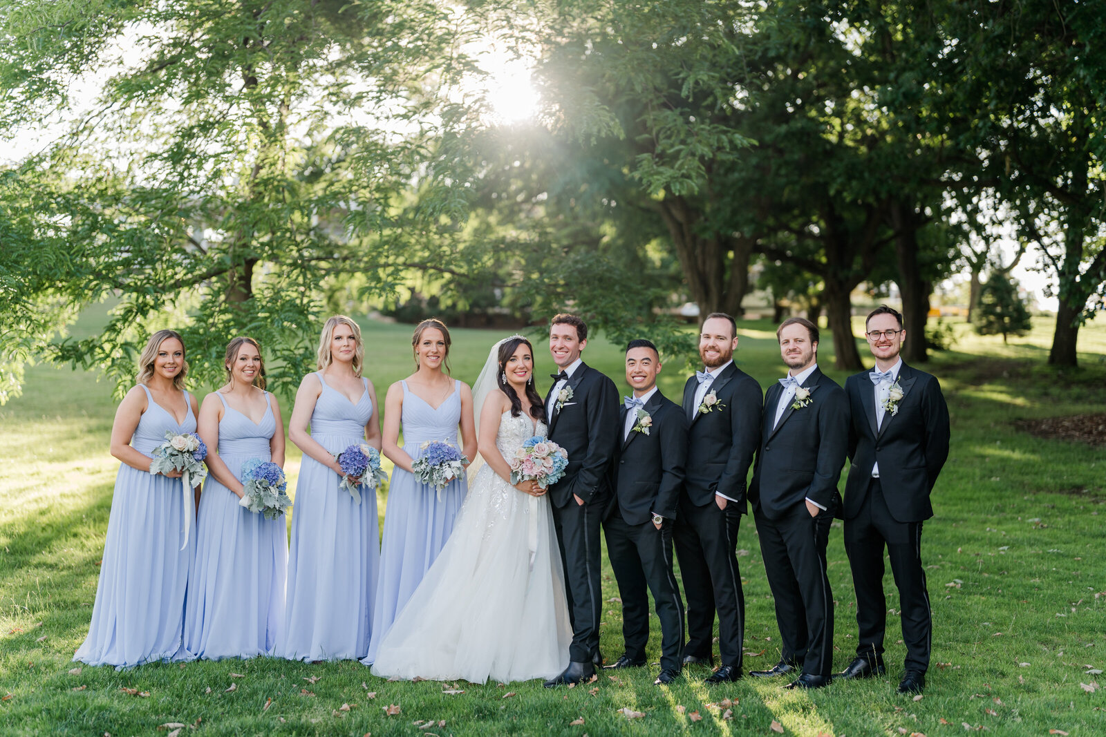 Wedding bridal party, in soft blue dresses and soft sunlight in nabckgroun