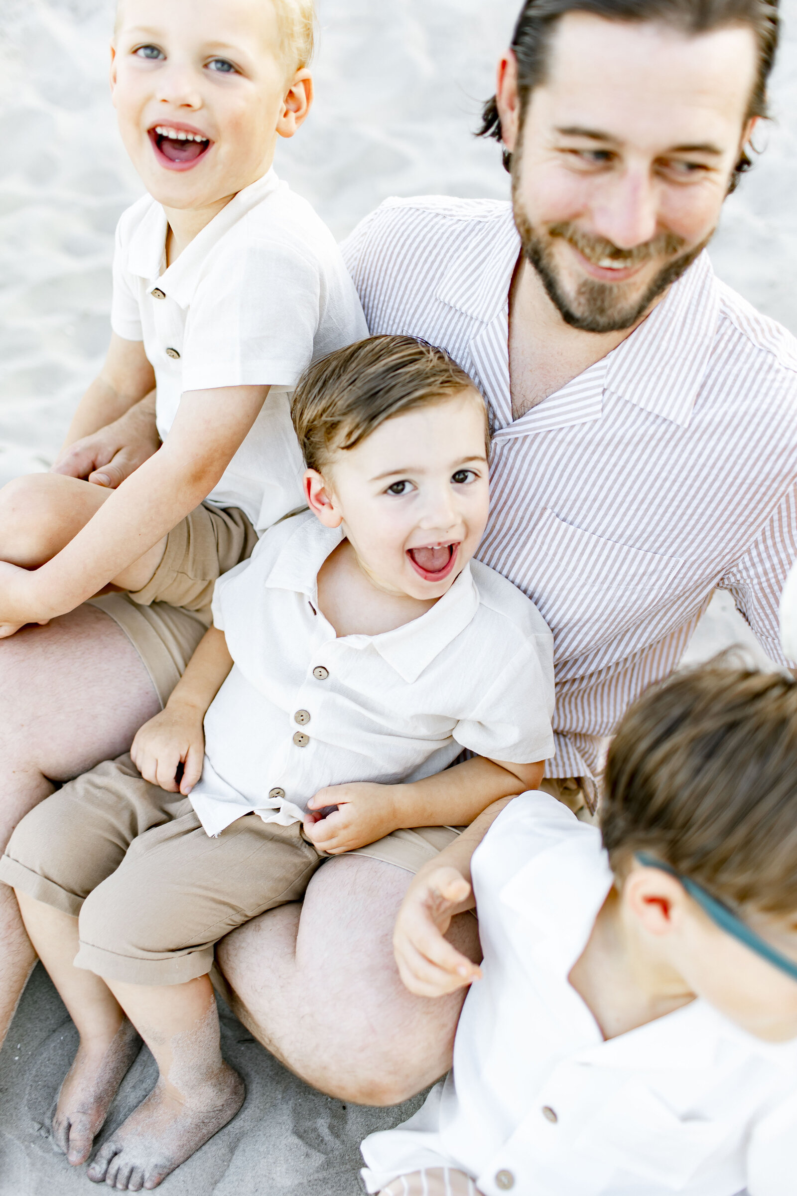 photo of son smiling on dads lap at the beach taken by ocean city photographer ally kimpton