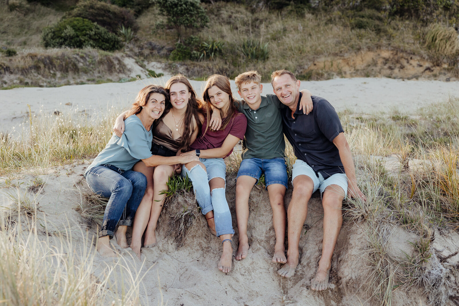 Big family hug for Mum Dad and the teenagers for a fun fmaily portrait session at Matapouri by Whangarei photographer Tracey Morris