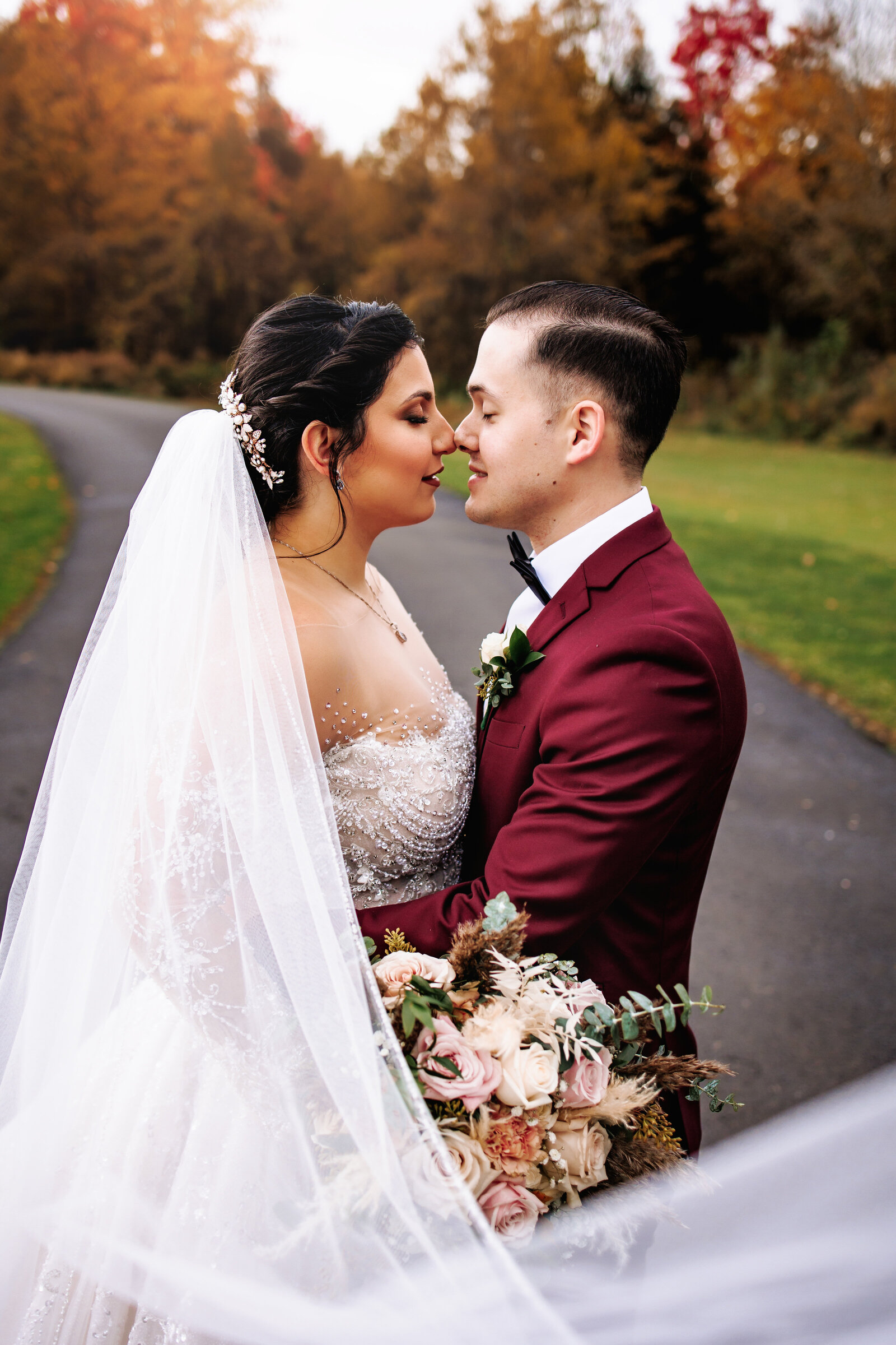 Bride and groom go in for a kiss amongst the beautiful fall foliage on their wedding day