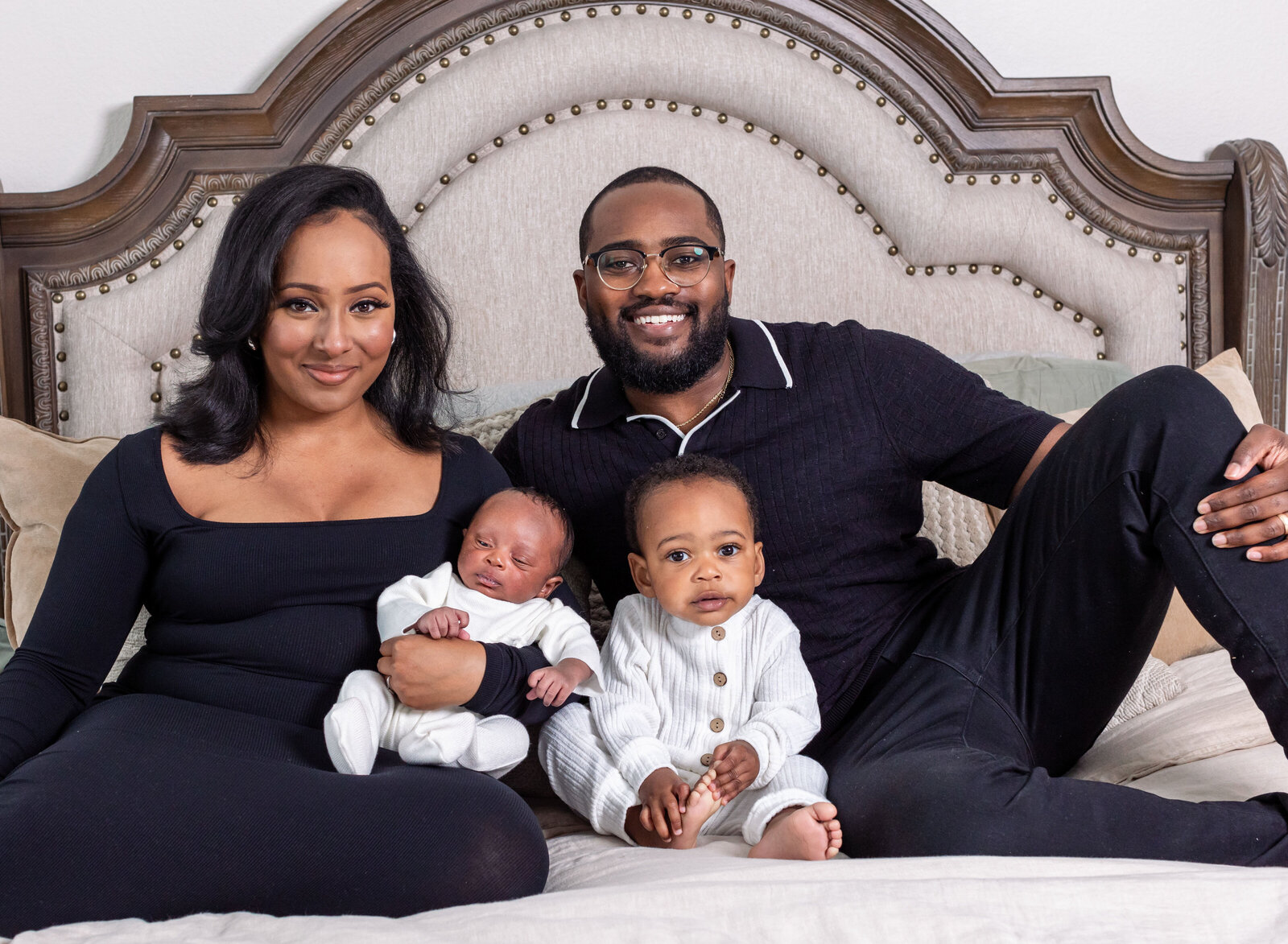 family with newborn on bed and big brother