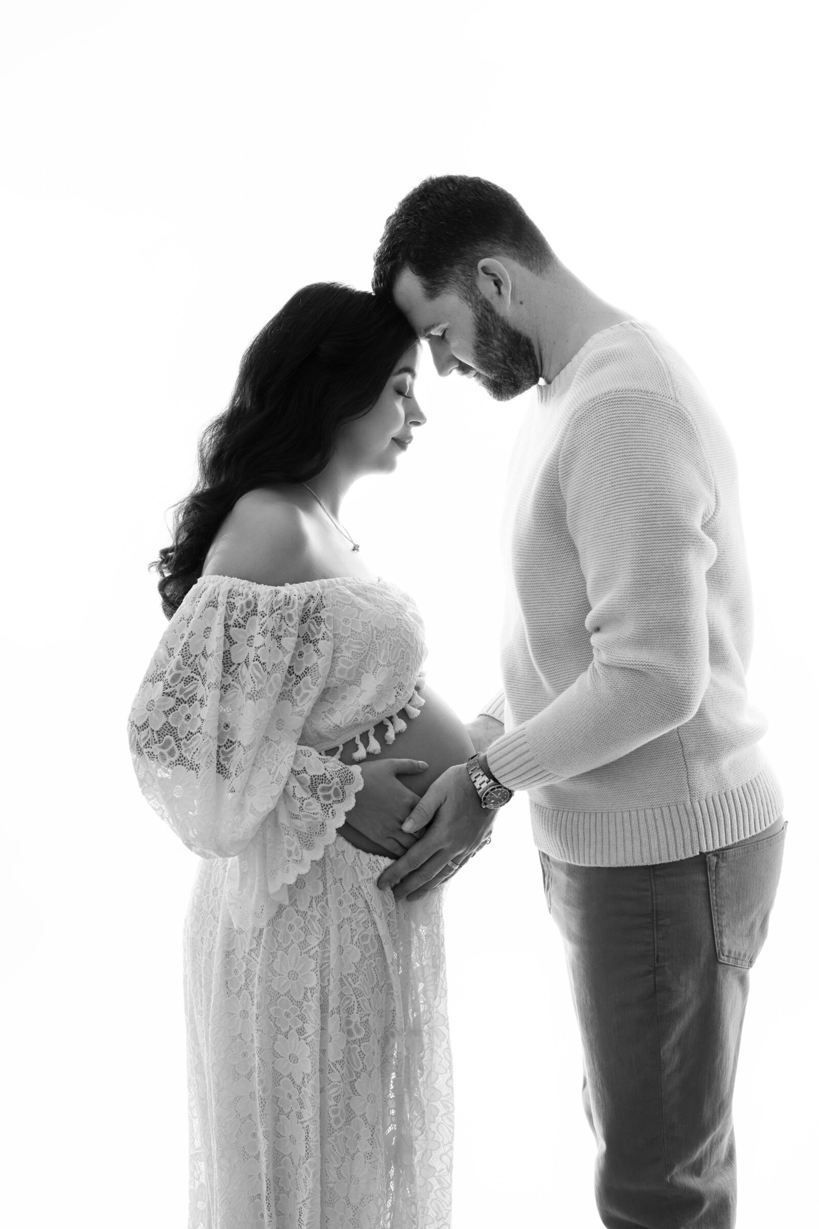 Mom and dad holding baby bump with heads together, dreaming of baby. Pregnancy photo taken by Jenni. Nikki Photography at Atlanta Photo Studio.  
