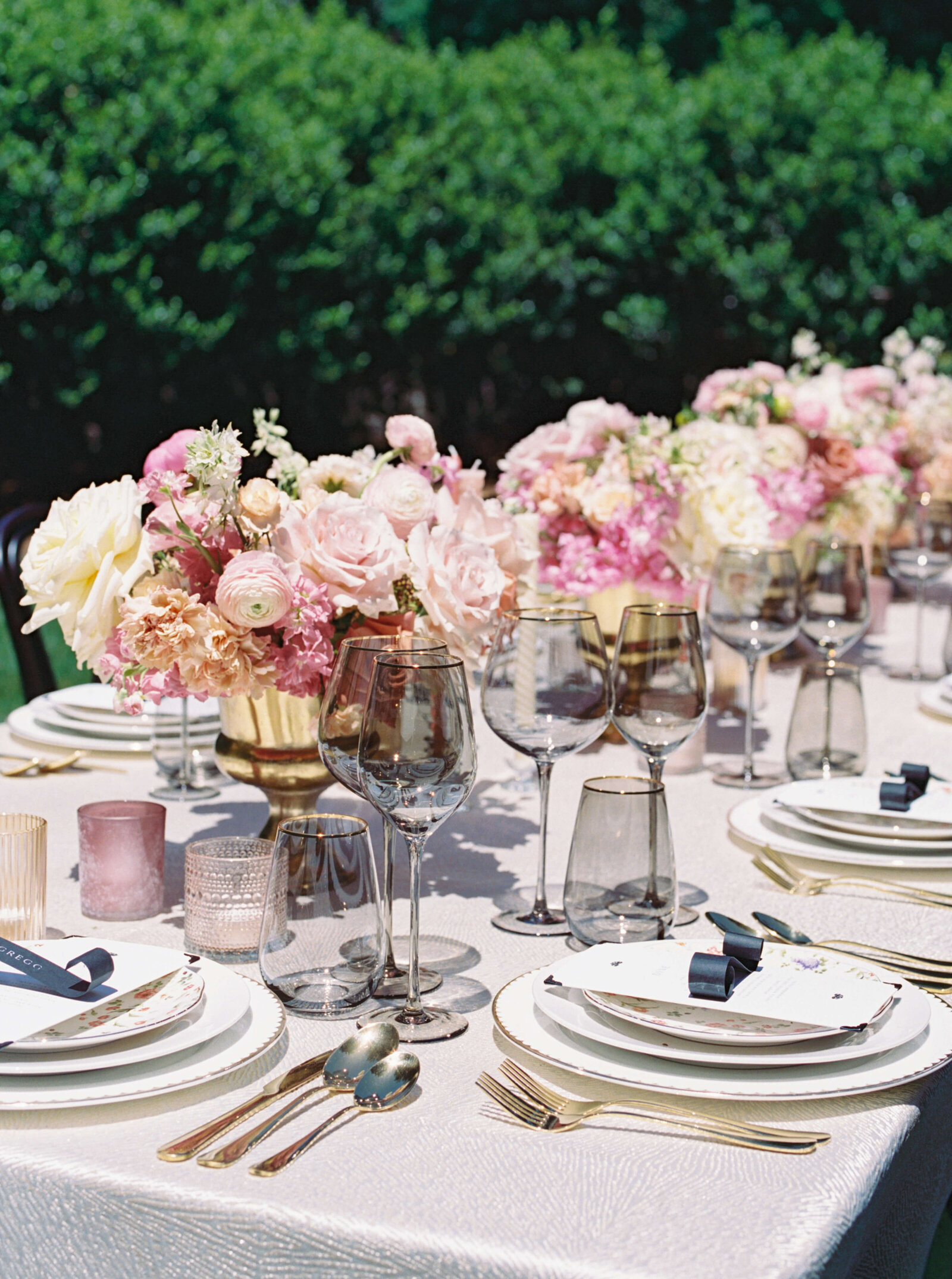 A beautifully set table with pink flowers acts as the head table for the bride and groom and their bridal party