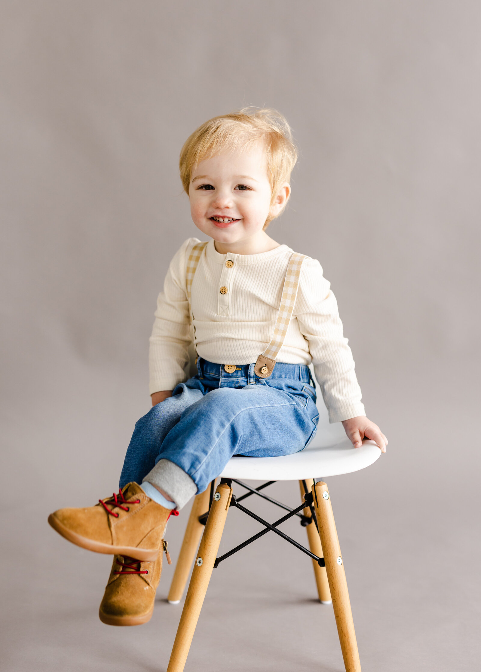 Young boy sits on a stool and smiles during his studio family session in Londonderry, New Hampshire