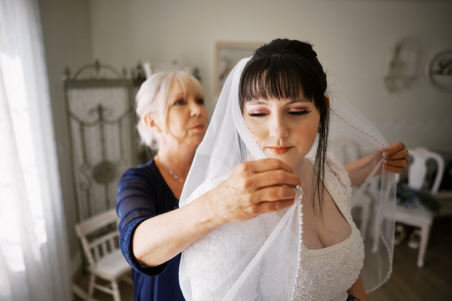 Mother of the bride helps get the veil on.