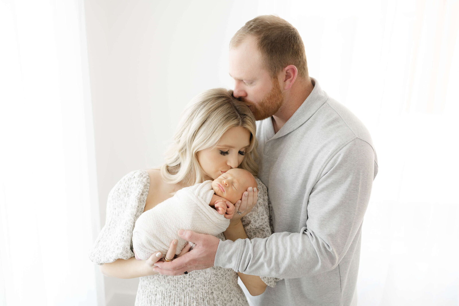 precious baby sleeping as mom and dad share a sweet kiss near downtown okc