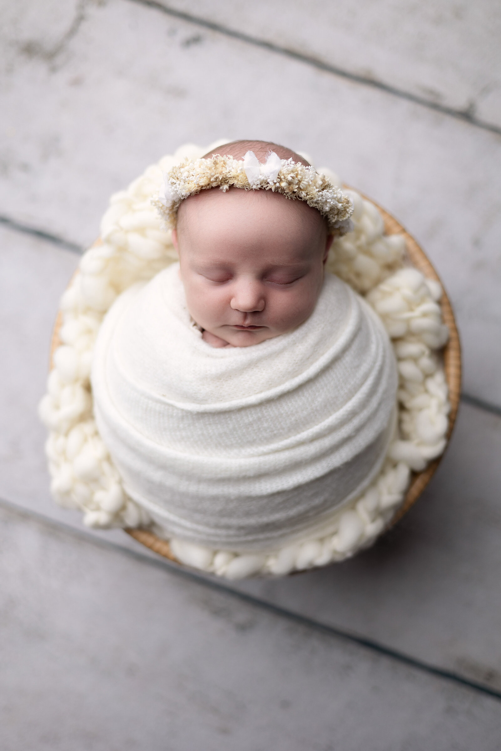 Newborn girl wrapped in cream wearing floral halo