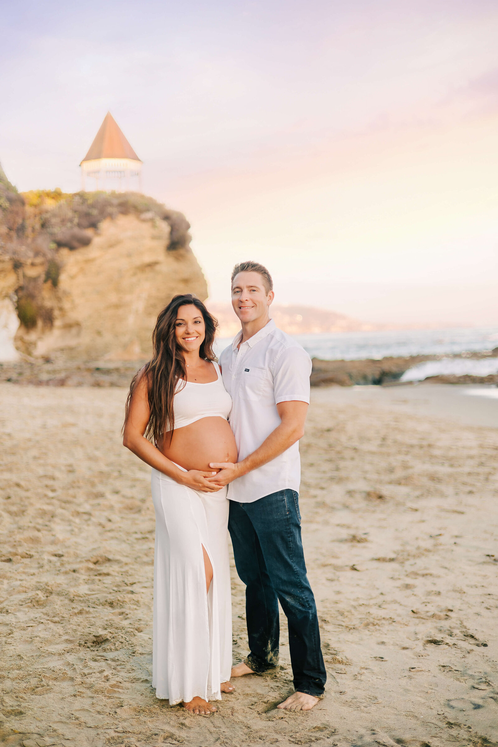 Husband wife embraced during maternity session in Laguna Beach, CA.