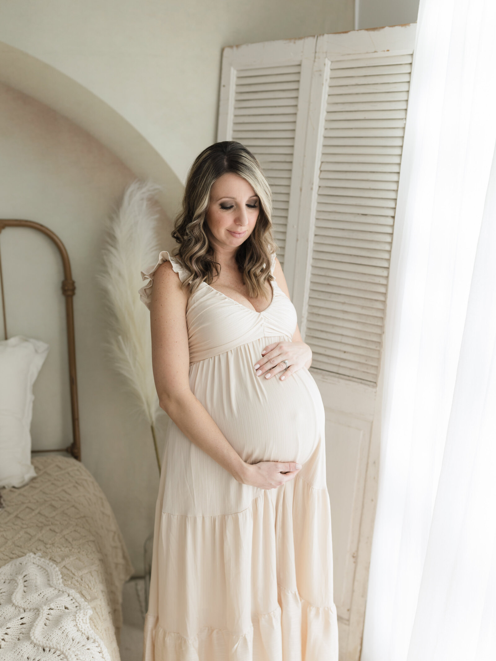 pregnant mother in cream maternity gown holding belly for maternity photoshoot cleveland maternity photographer