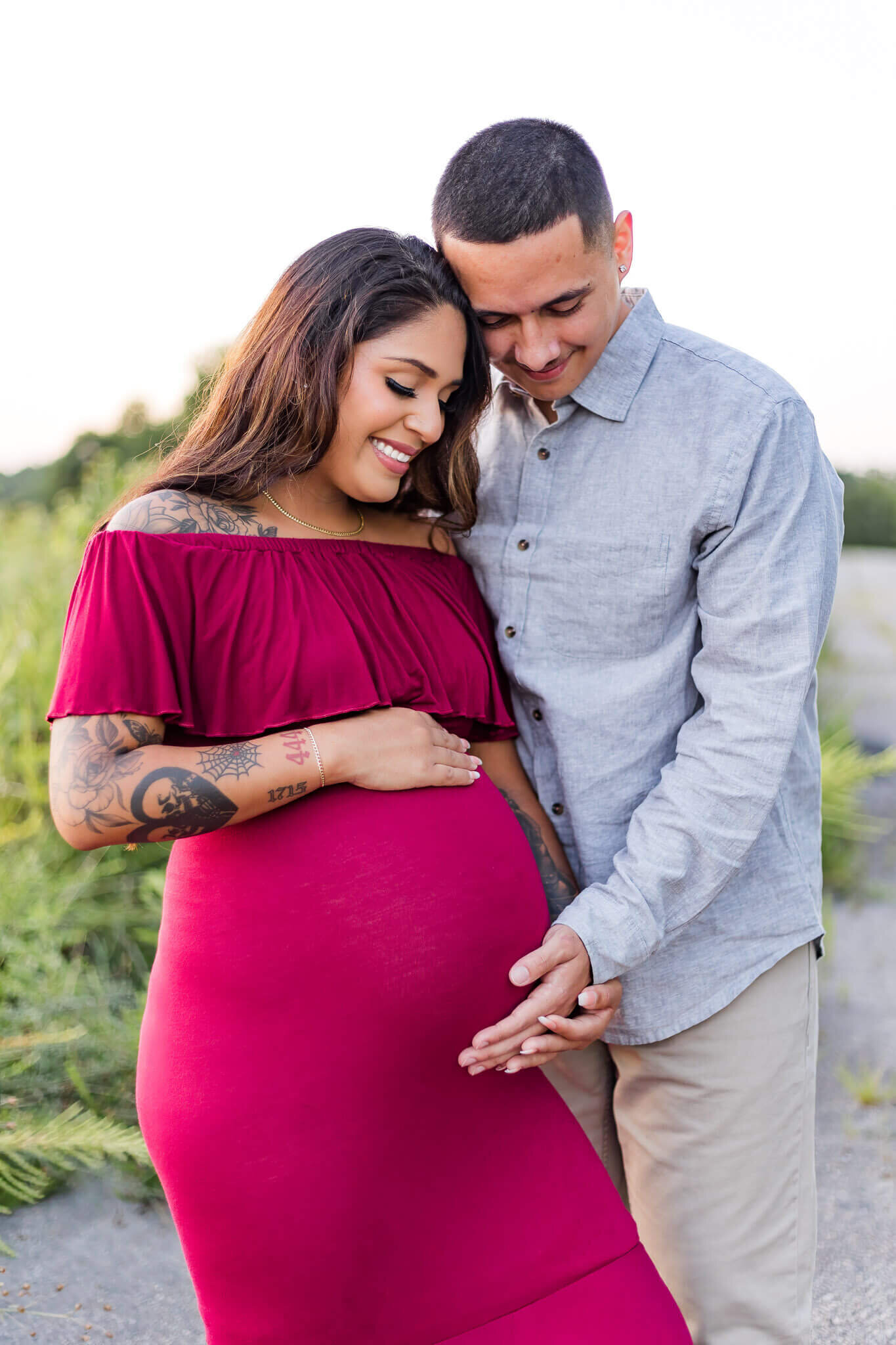 A couple expecting their first child holding mom's belly and smiling.