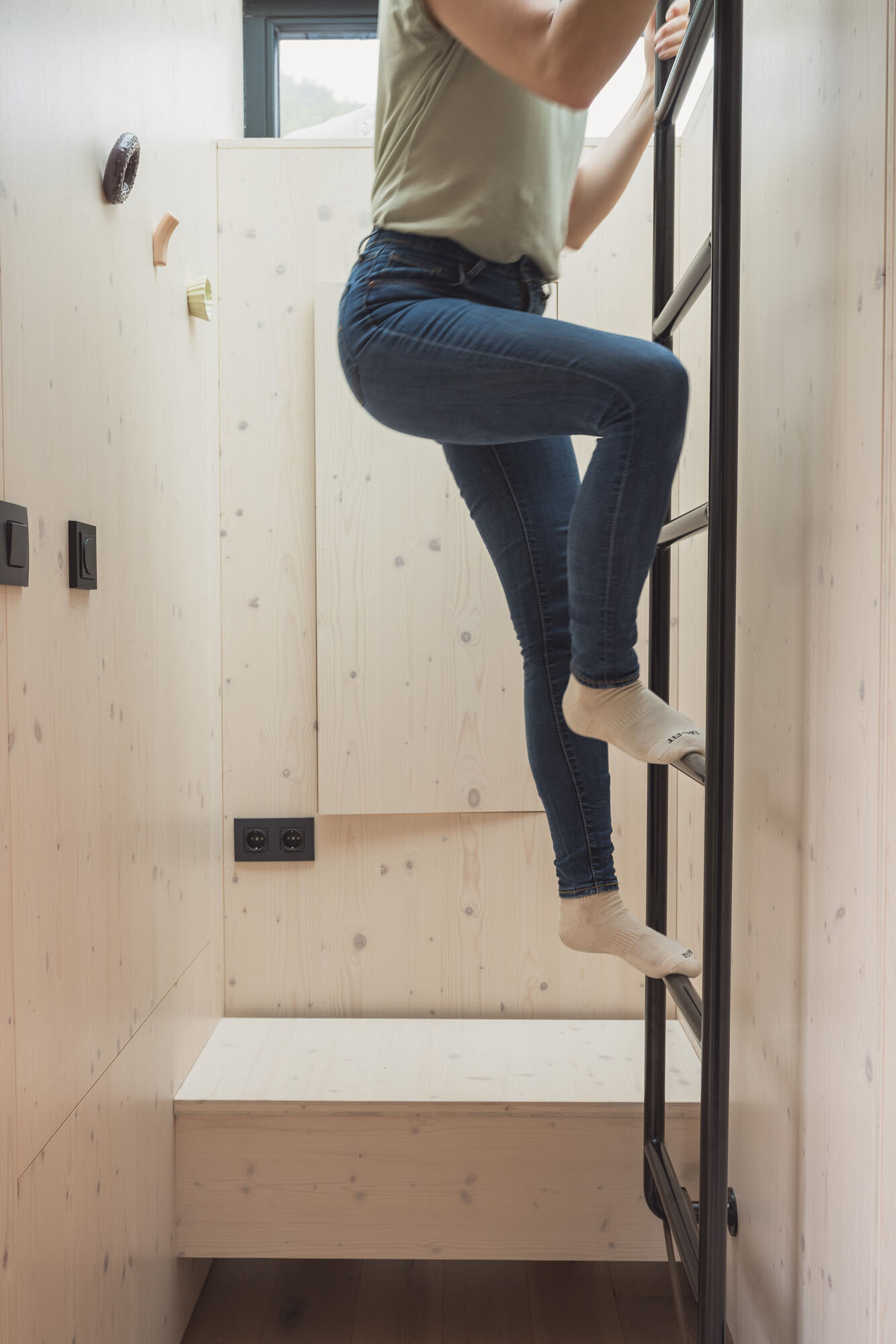 Person climbing up to the top bunk in a Tiny Home at The Campus Alps.com, offering unique and cozy accommodation for private getaways or company retreats in the heart of the Alps.