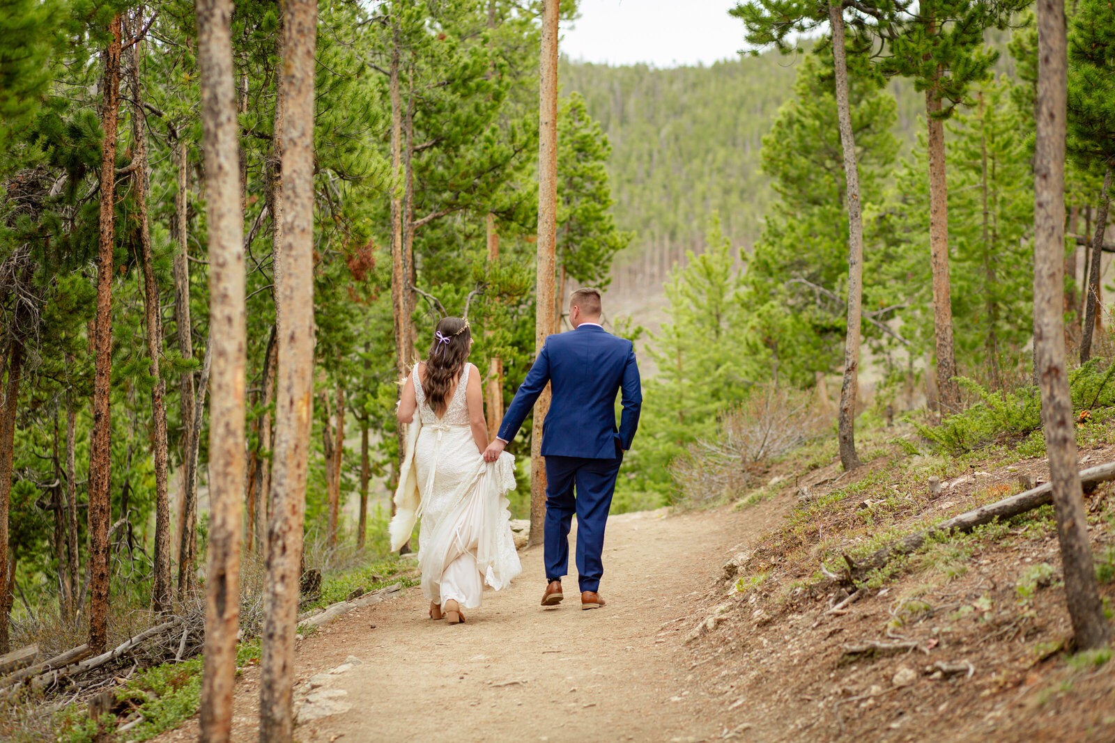 Bride and groom walk down a trail after their ceremony
