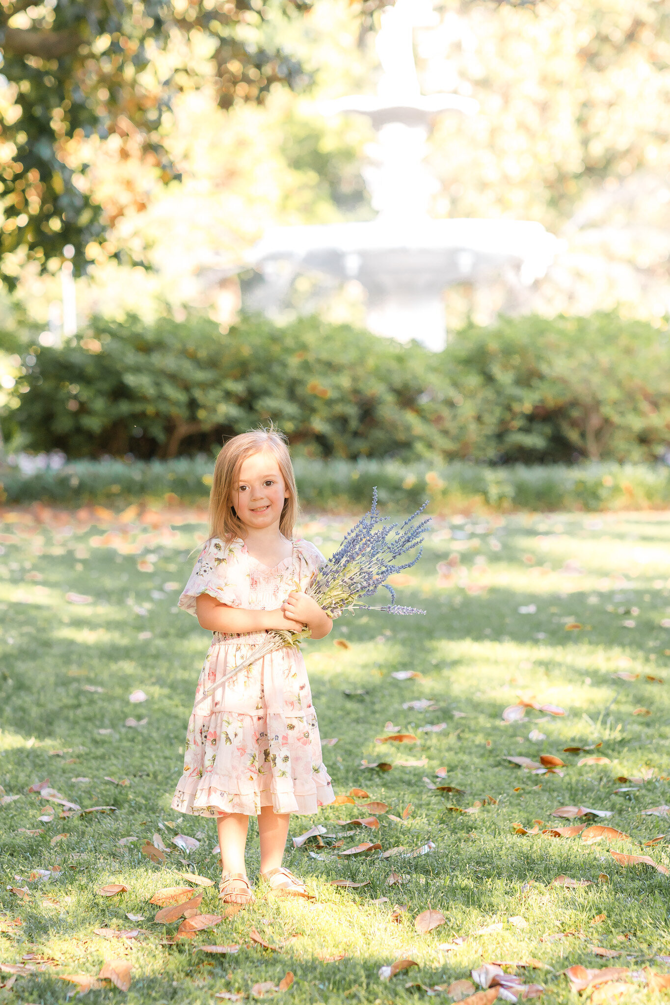 Little girl holding flowers at Forsyth Park in Savannah, Ga during their family session