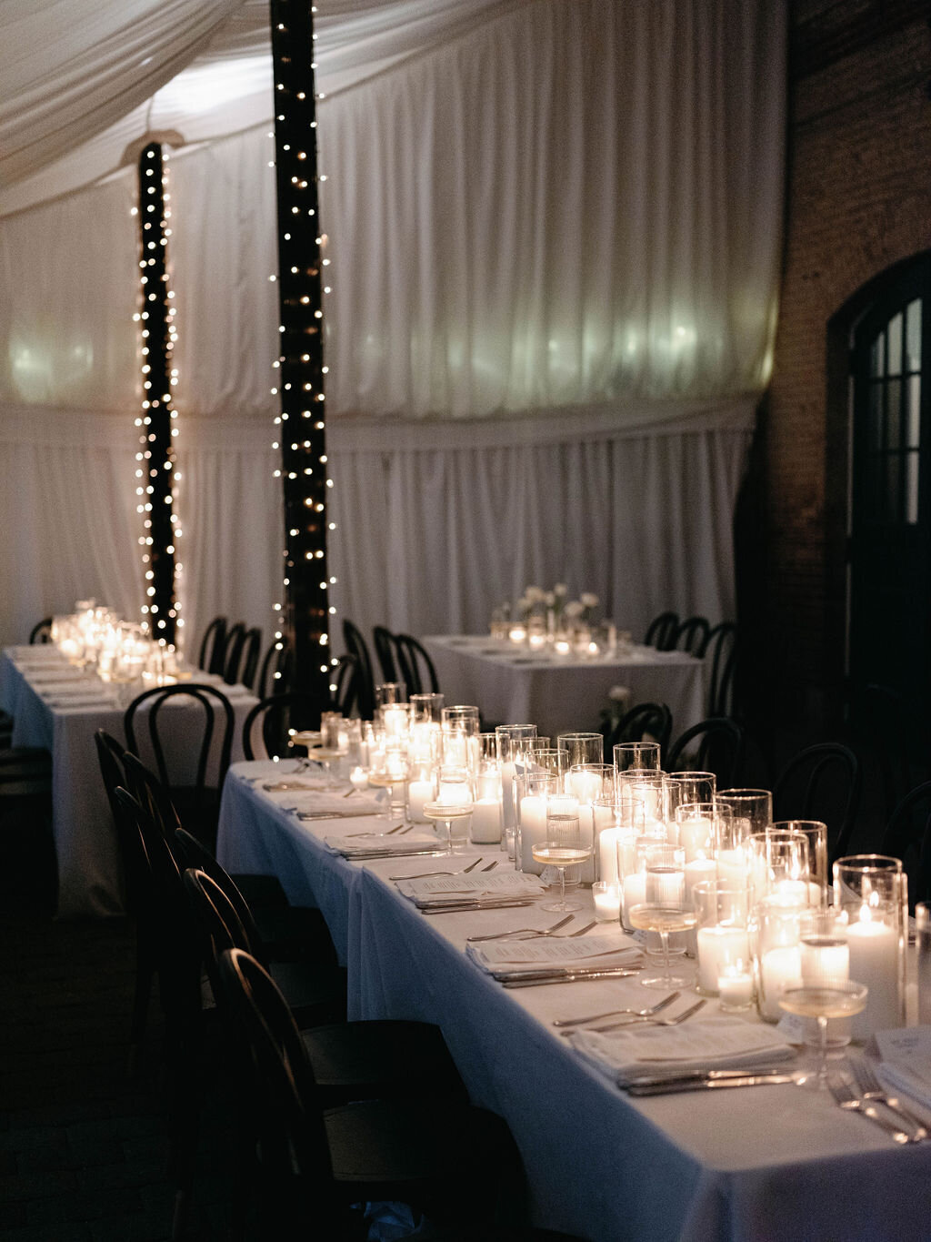 Long guest tables at the receptions at the Evergreen Museum Carriage House with an abundance of ivory pillar candles.