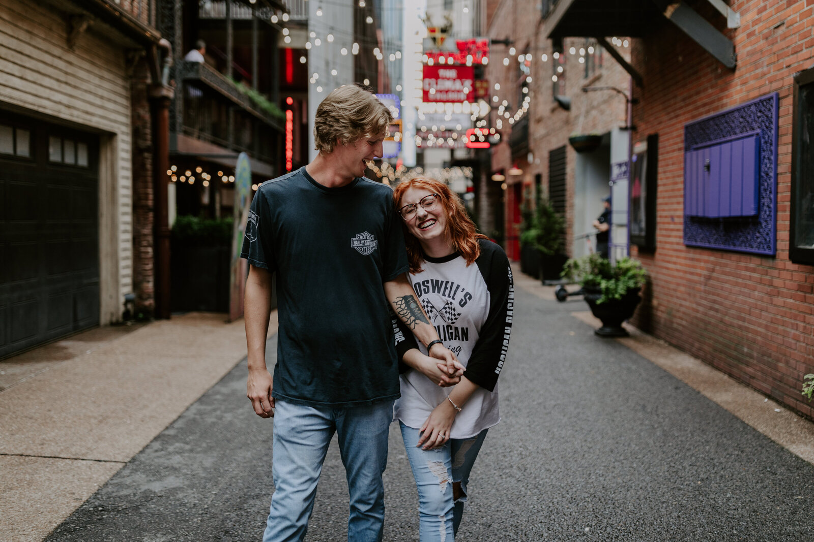 Couple holding hand and laughing while walking down painters alley in Nashville