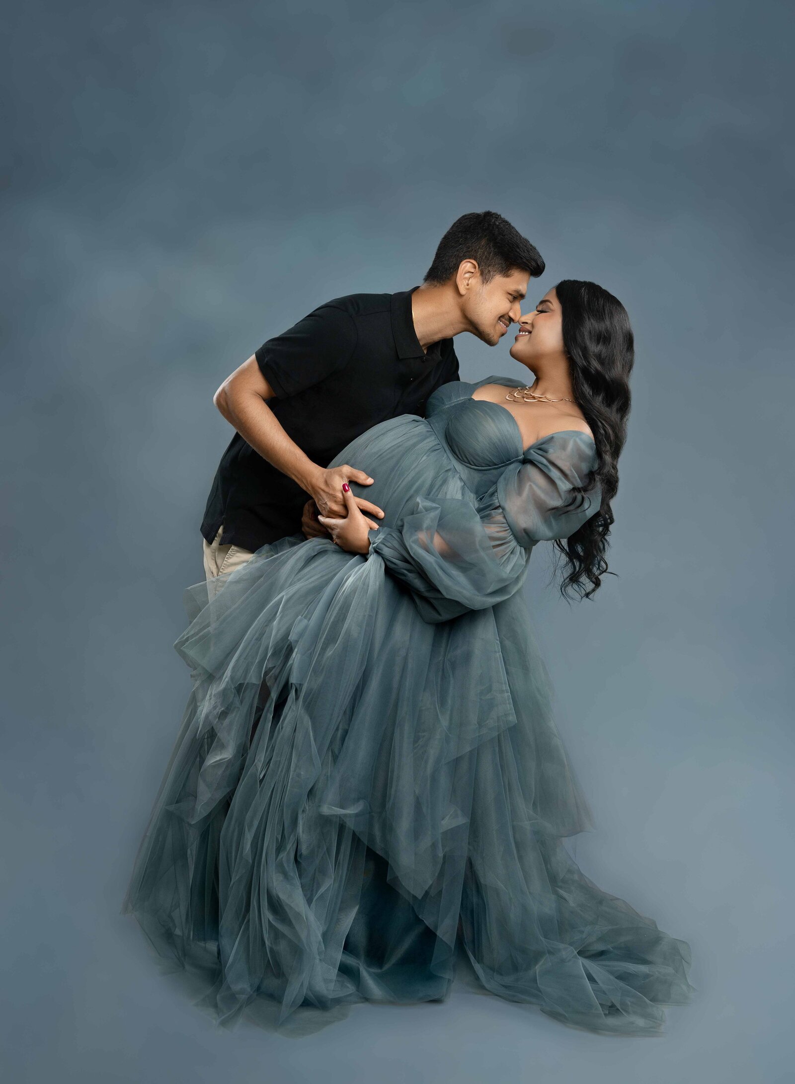 Pregnant Mom in blue gown and dad in black shirt taking Maternity photos at Atlanta photo studio.