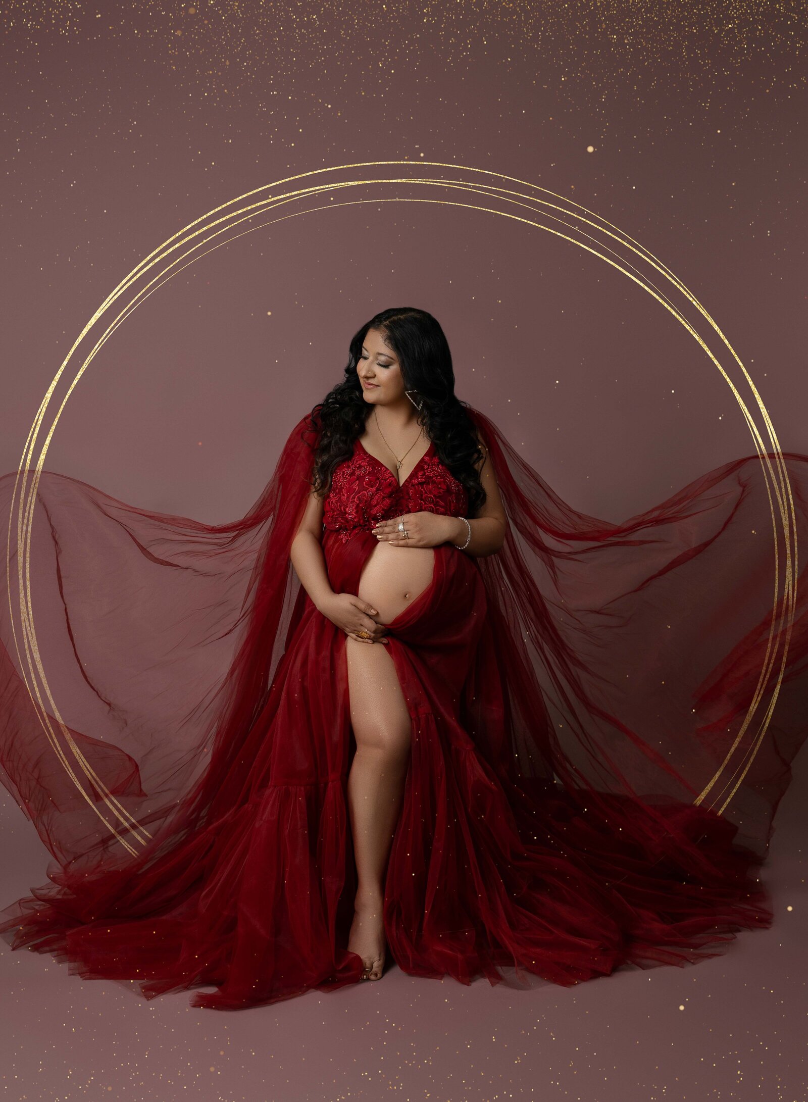 Mom in red dress, holding baby bump, and dress tossed in wind. Photo taken at Atlanta Photo Studio.