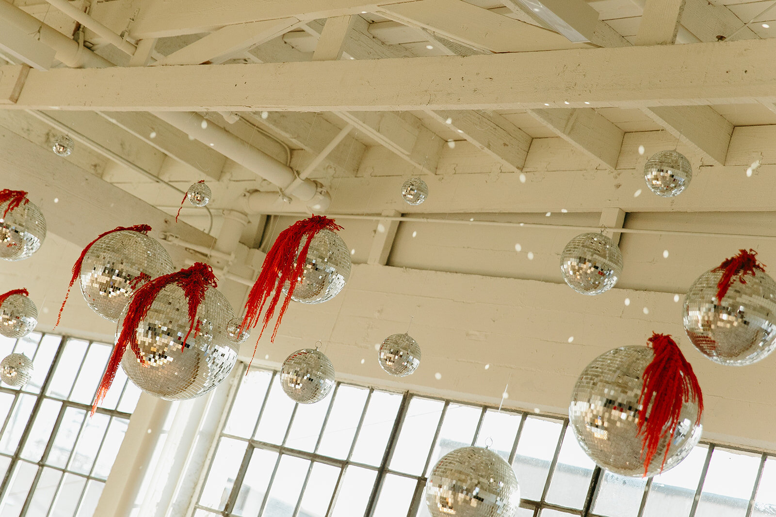 Hanging disco ball wedding installation with red fringe accents at a modern Los Angeles venue, styled by Jasper & Lane Events